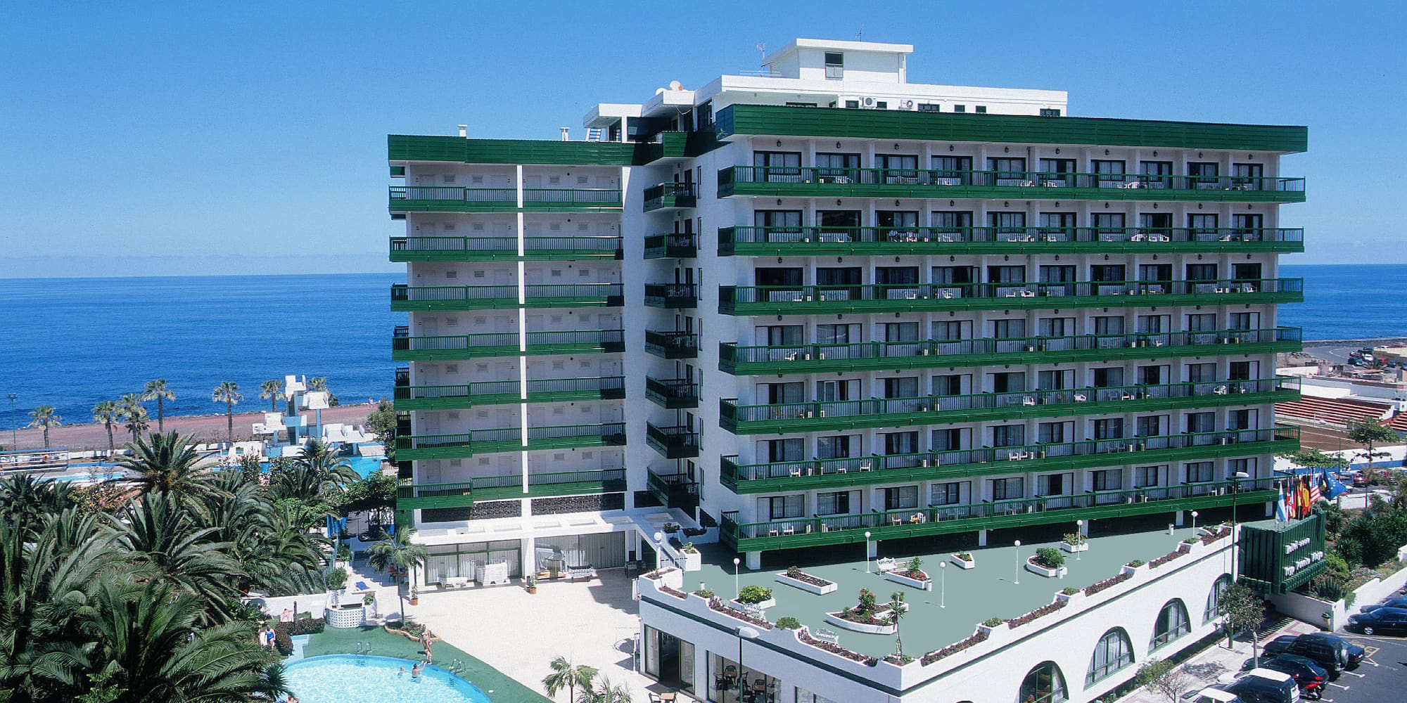 a large building with a pool and cars parked next to it