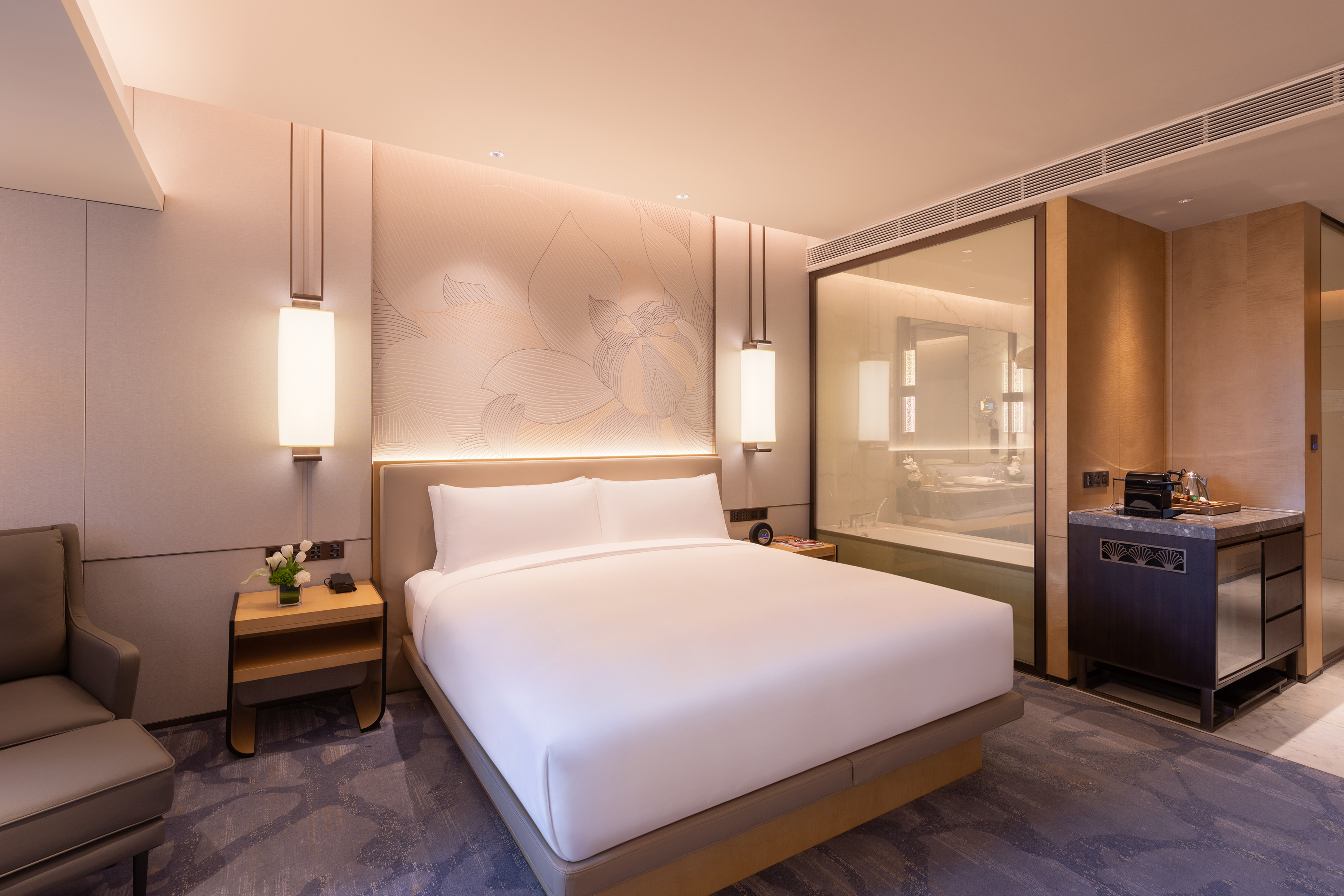 Modern luxury hotel room with large bed, sleek design, and open-concept bathroom.