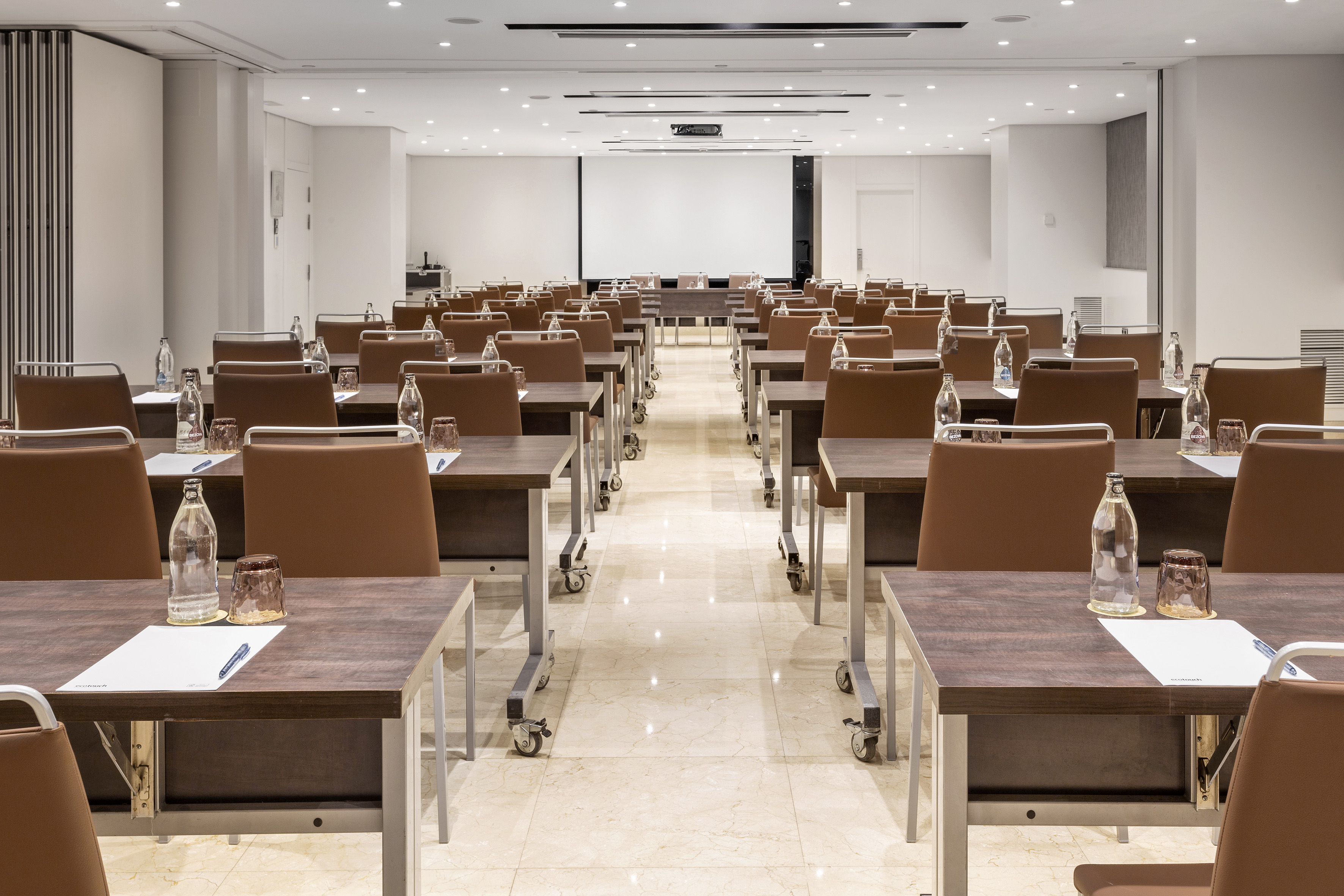 Modern conference room with classroom setup, large screen, and individual desks.