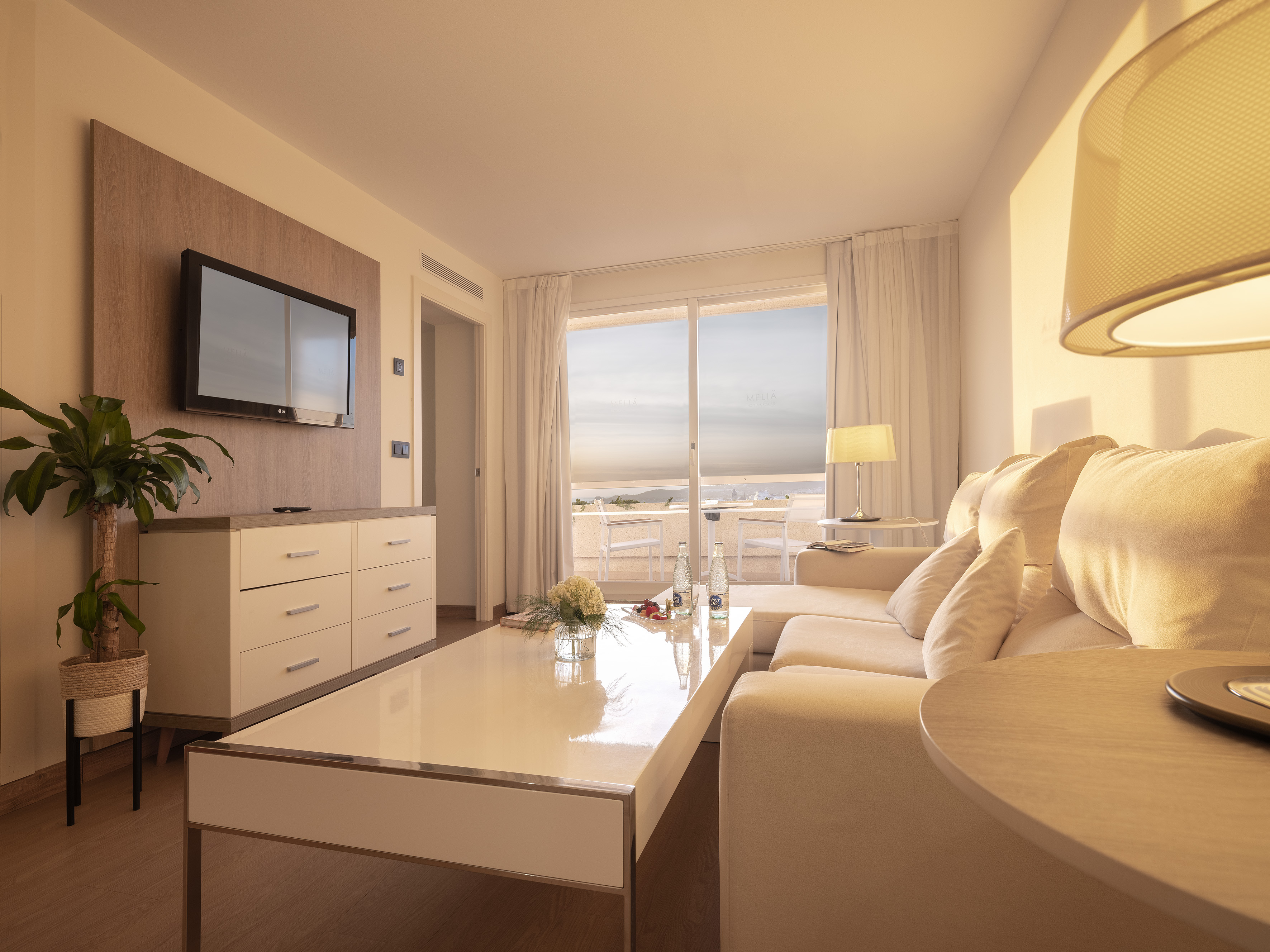 Modern hotel living room with ocean view balcony and cream sofa.