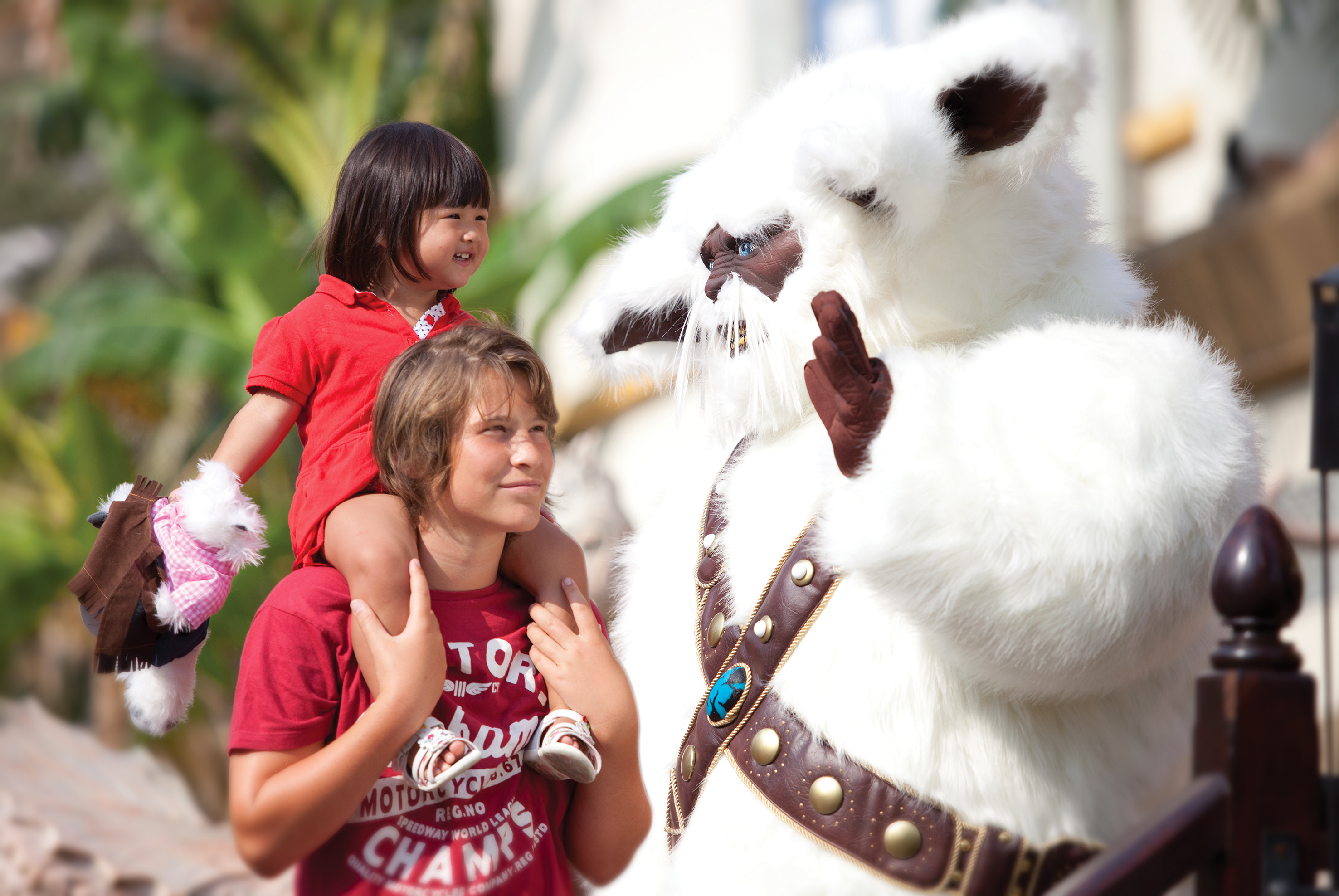Smiling child on shoulders meets furry white costumed character.