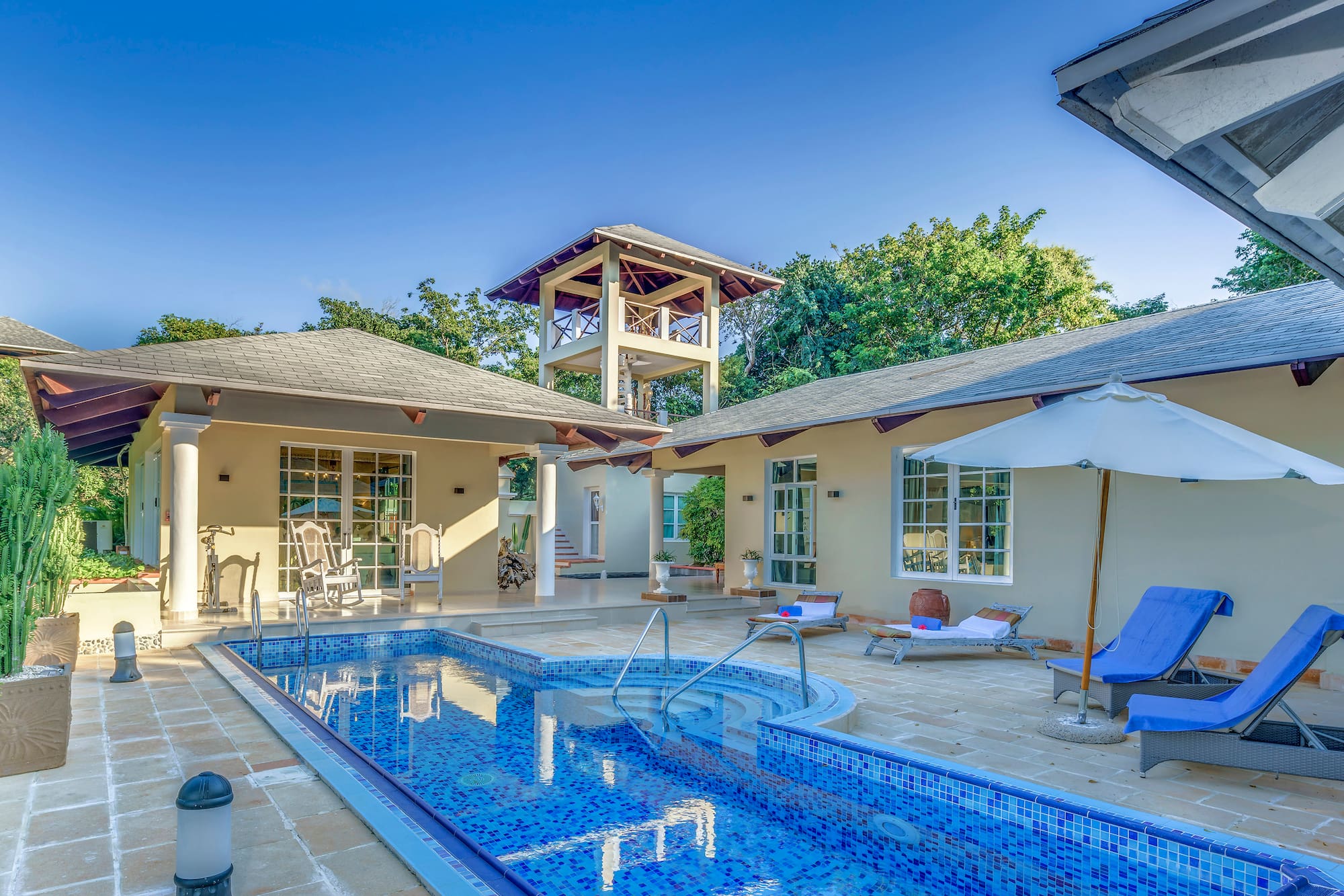 a swimming pool with a white umbrella and a white tower