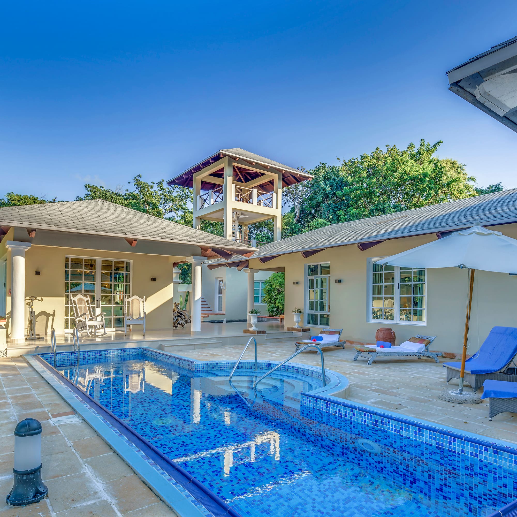 a swimming pool with a white umbrella and a white tower