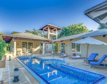 a swimming pool with a white umbrella and a white tower