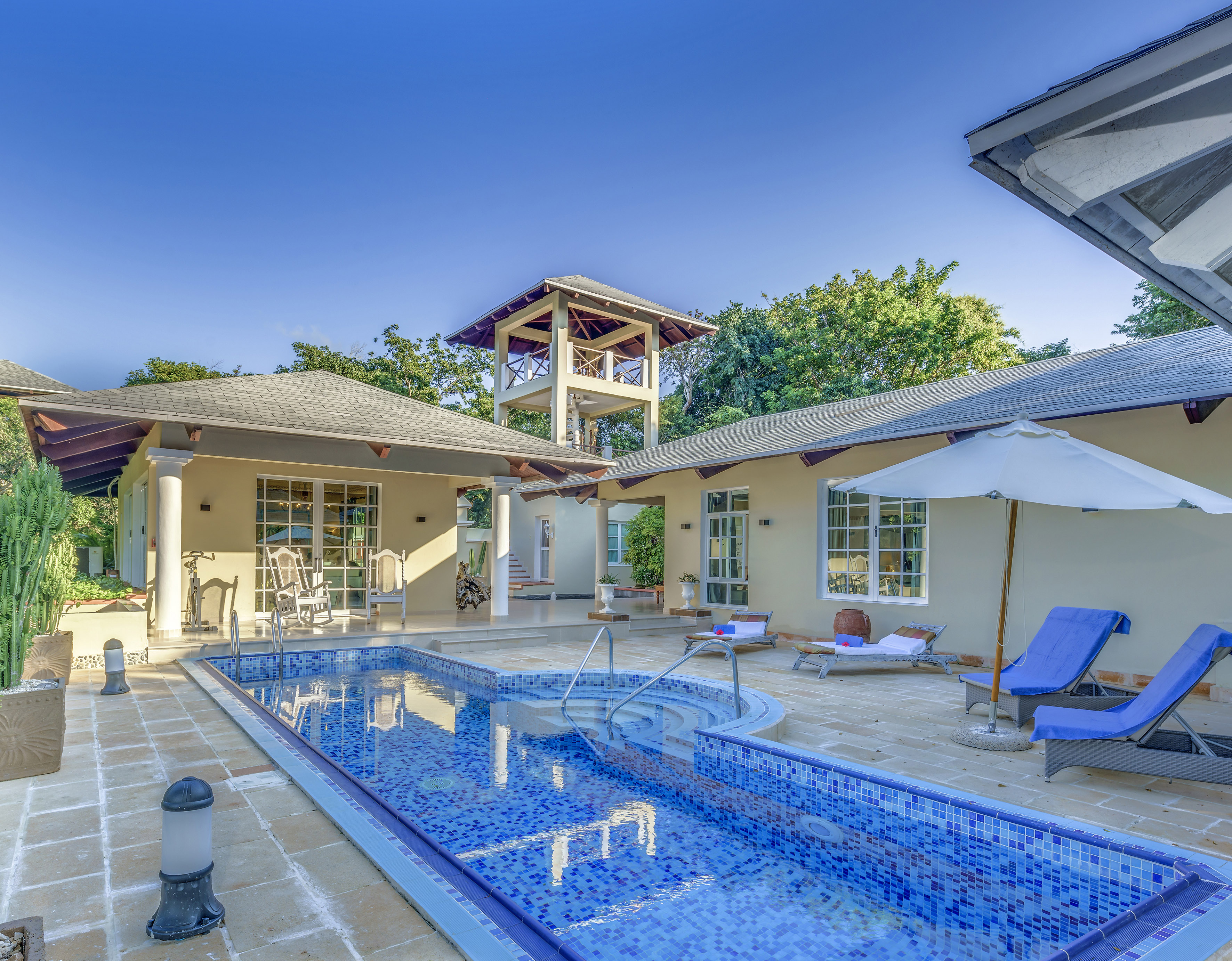 a swimming pool with a white umbrella and a white tower