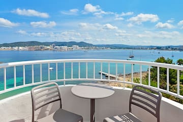 a table and chairs on a balcony overlooking a body of water