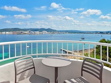 a table and chairs on a balcony overlooking a body of water