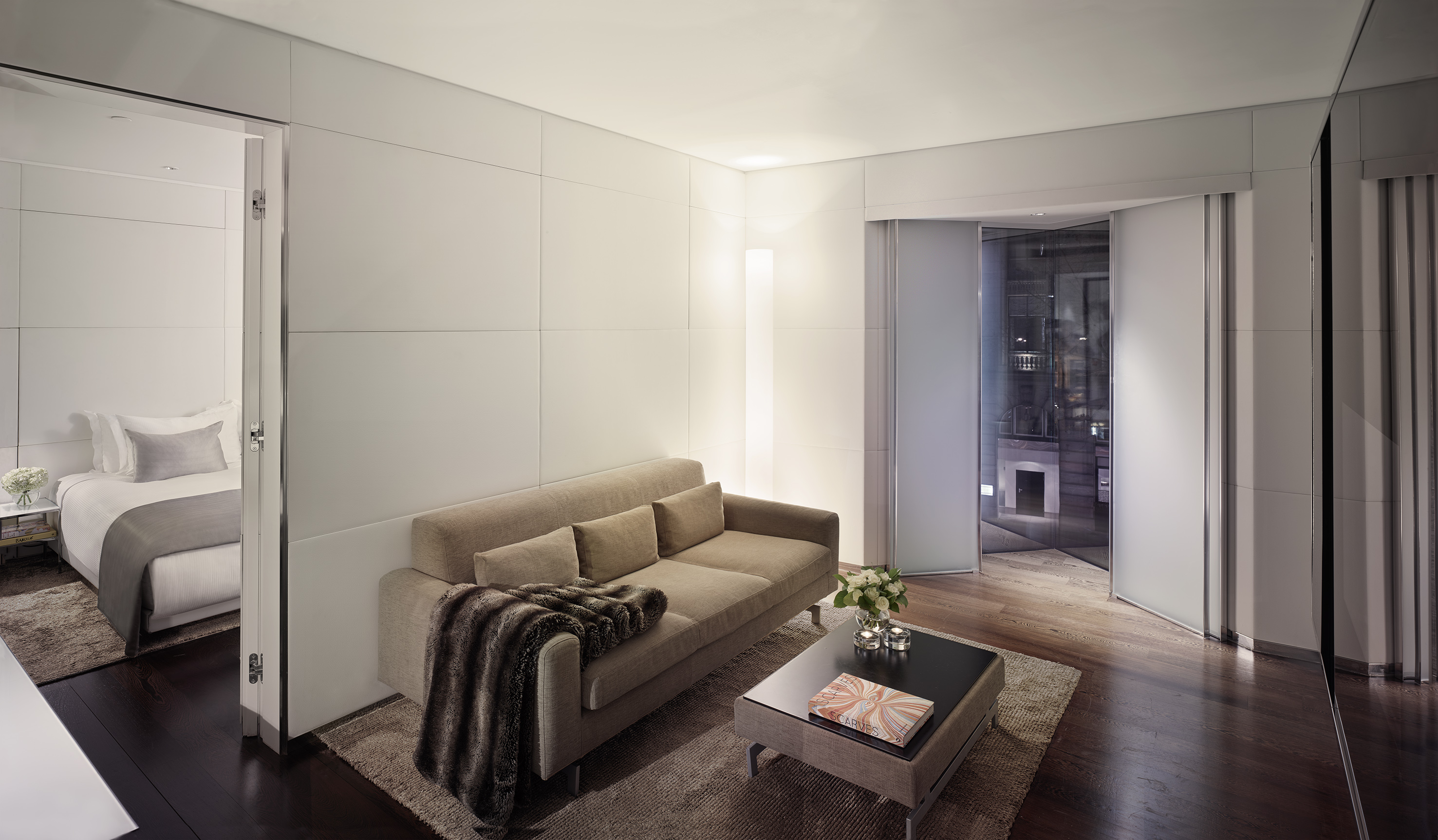 Modern suite: living room with sofa, bedroom, and city view.