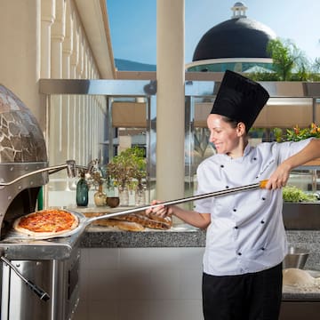 a woman in a chef's uniform making pizza