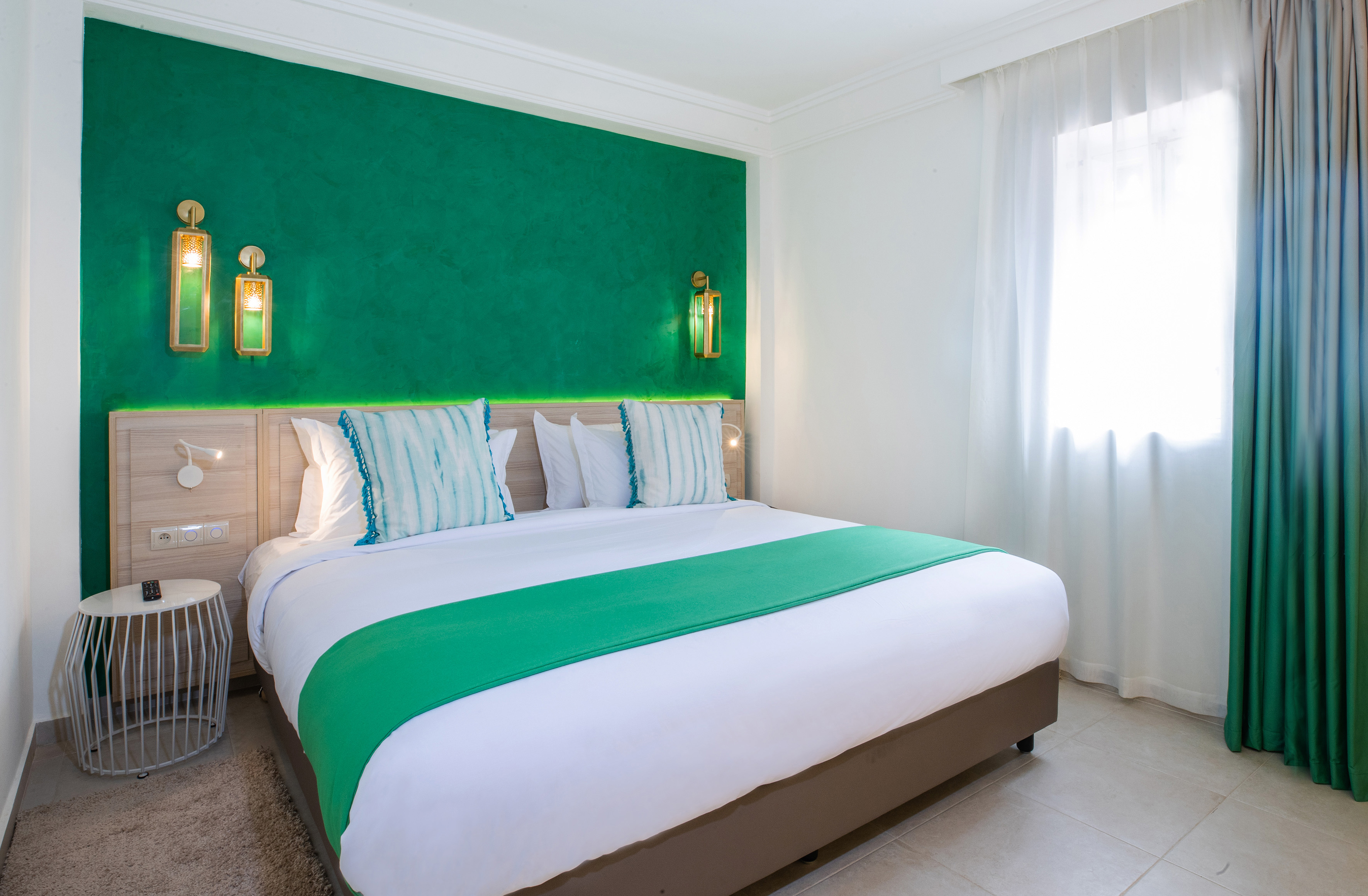 Green accent wall bedroom with king bed, gold sconces, and modern decor. - Family Room - SOL Oasis Marrakech, Marrakech