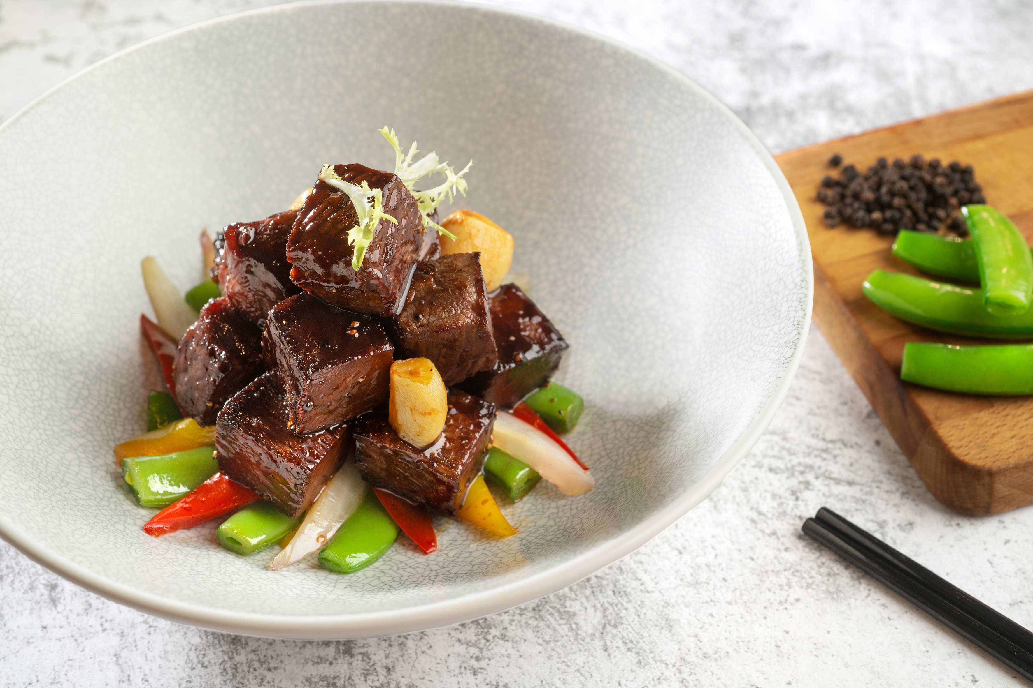 Glazed beef cubes with colorful vegetables, snap peas, and garlic.
