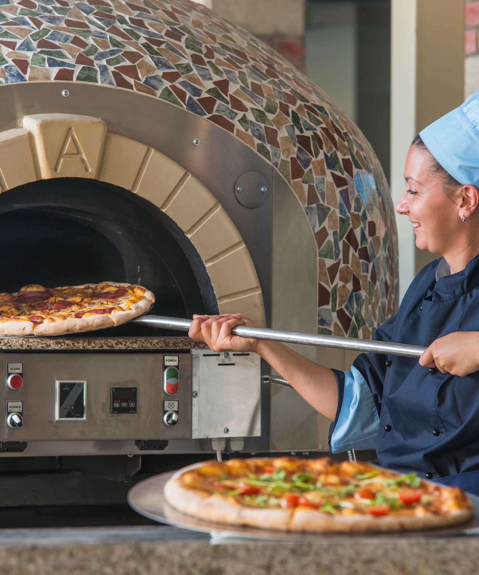 a woman in chef hat cooking pizza in a oven