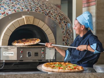 a woman in chef hat cooking pizza in a oven
