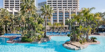 a pool with palm trees and a large building