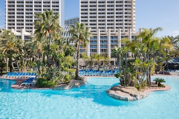 a pool with palm trees and a large building