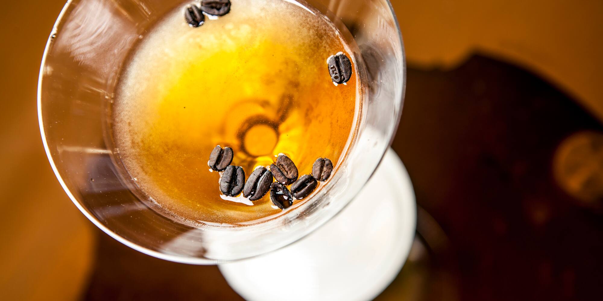 a glass with liquid and coffee beans in it