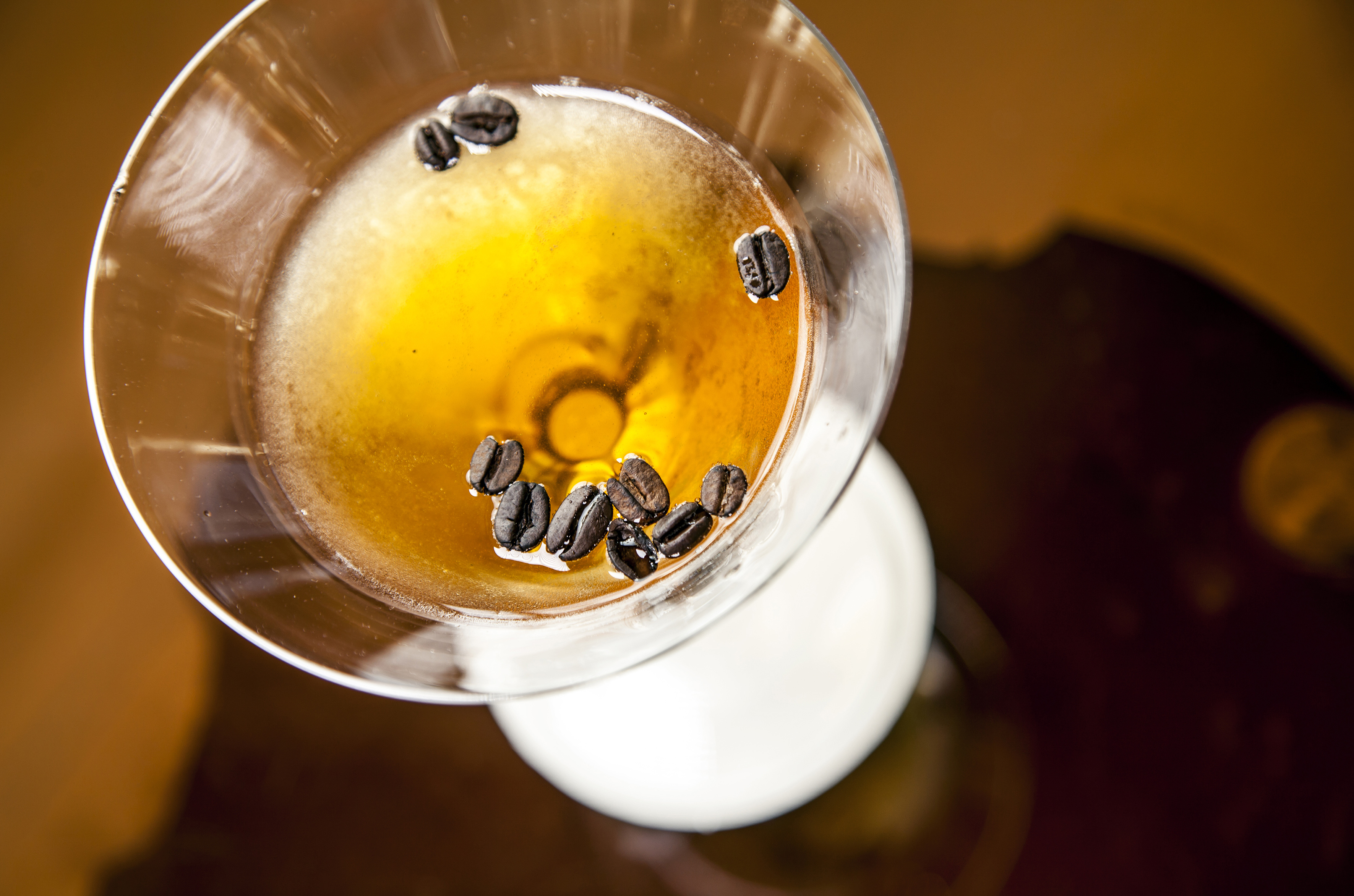 a glass with liquid and coffee beans in it