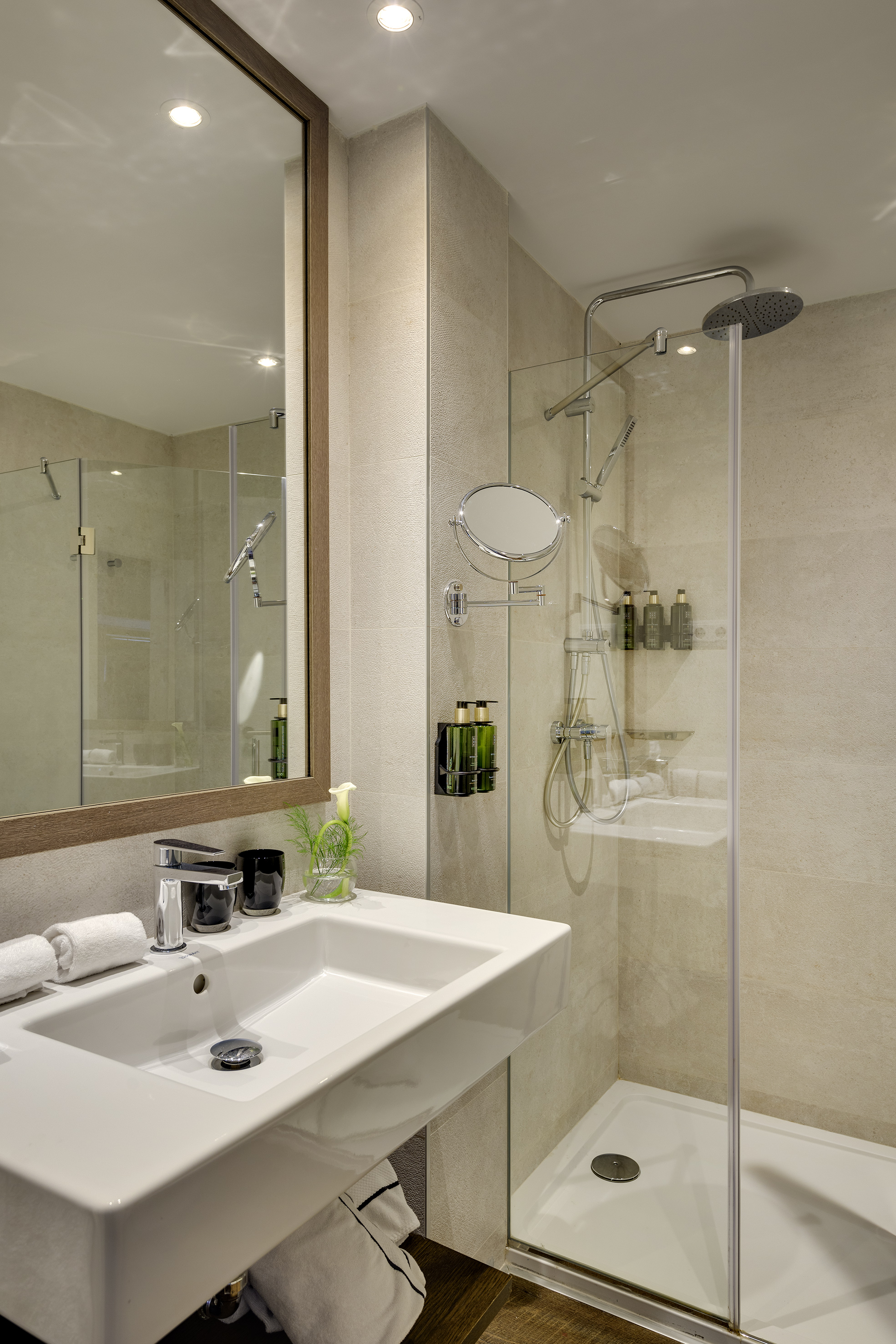 Modern bathroom with vanity, large mirror, and glass walk-in shower.