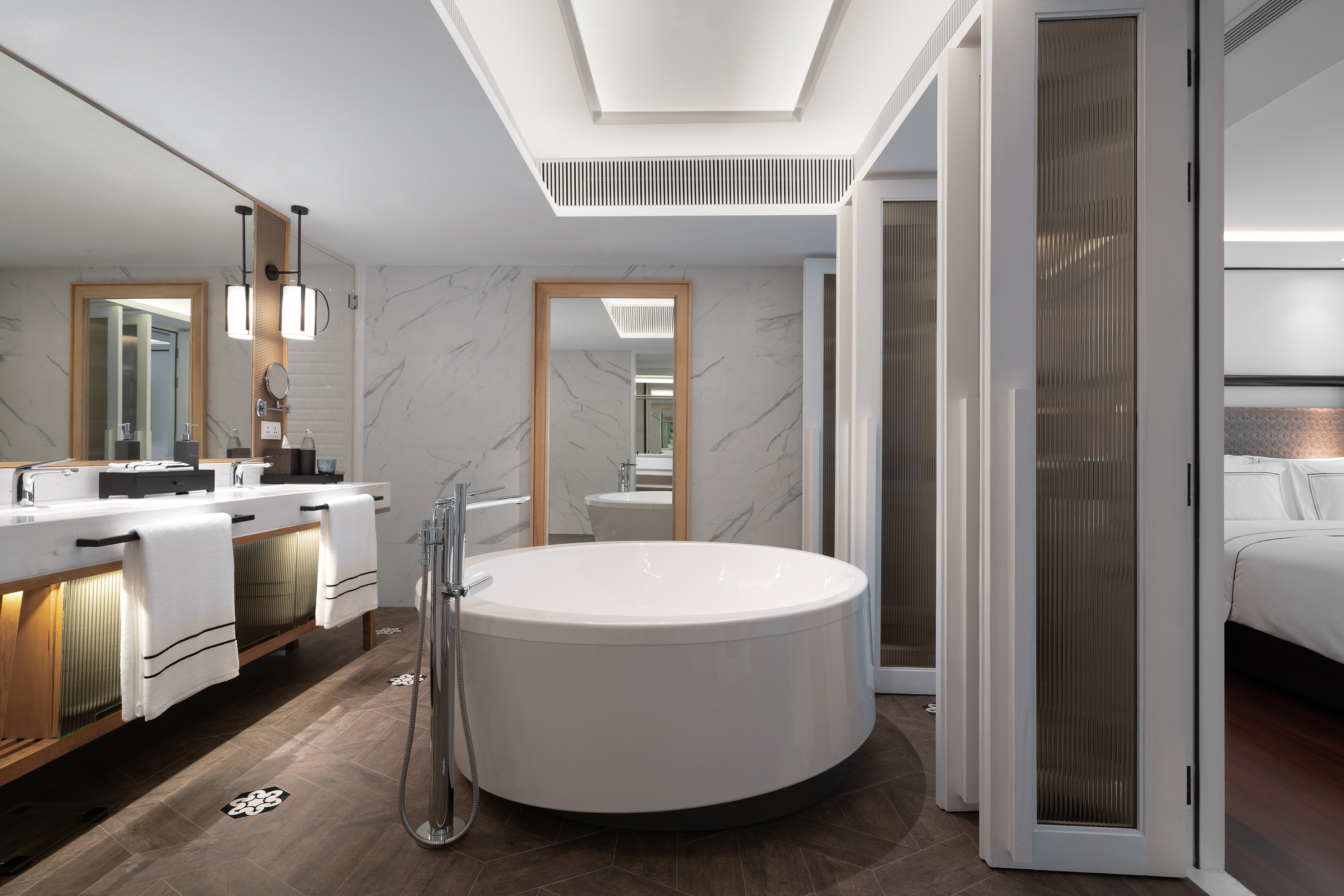 Modern en-suite hotel bathroom with freestanding tub, double vanity, marble.