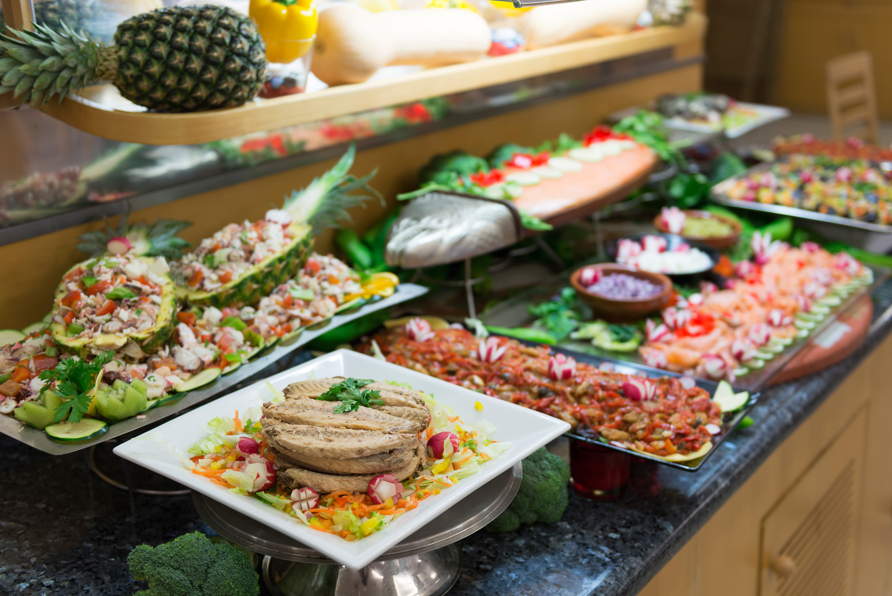 Abundant hotel buffet featuring pineapple ceviche, sliced fish, and fresh salads.
