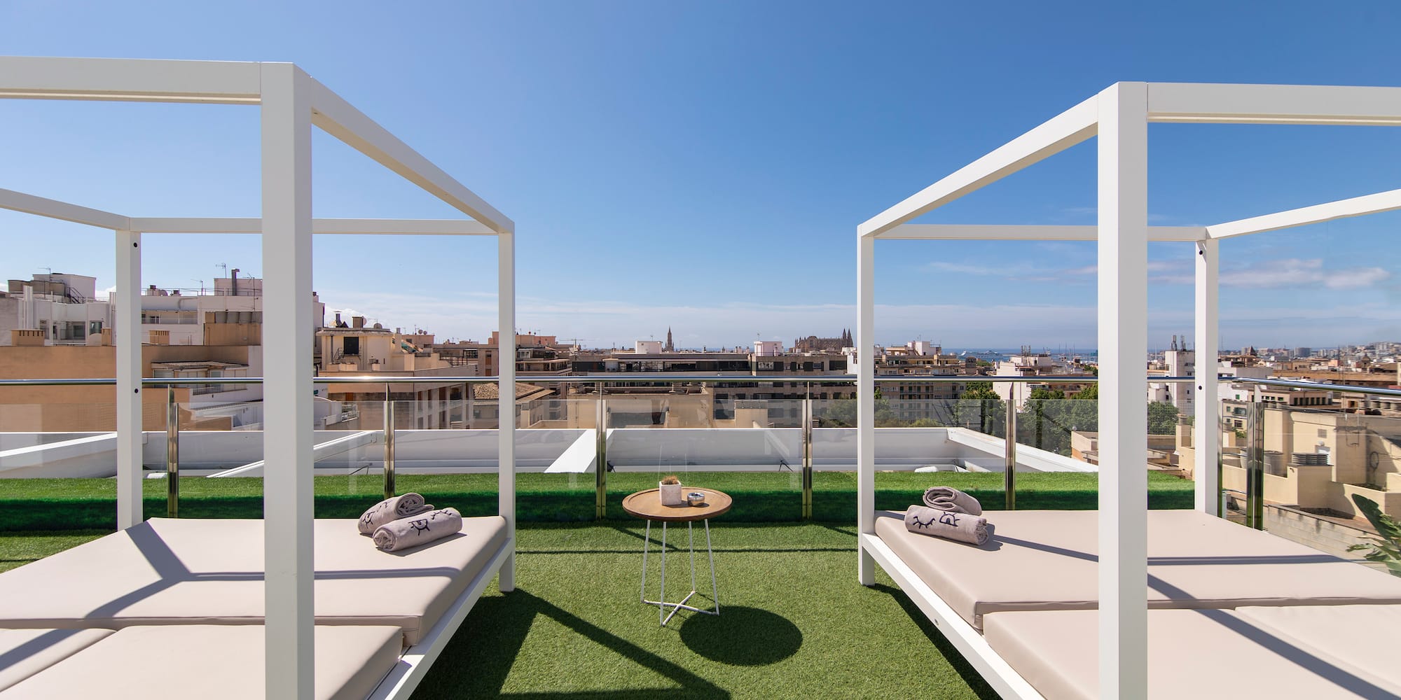 Luxury rooftop terrace with white canopy daybeds, city view.