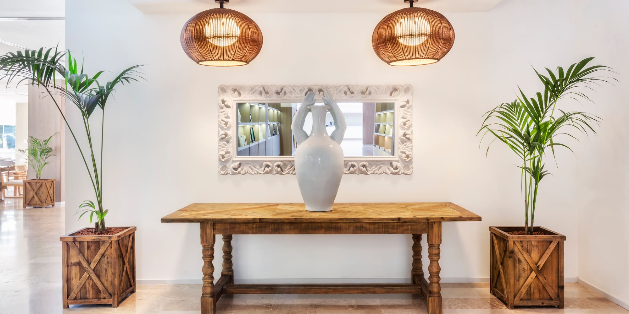 a white vase on a table with two plants in pots