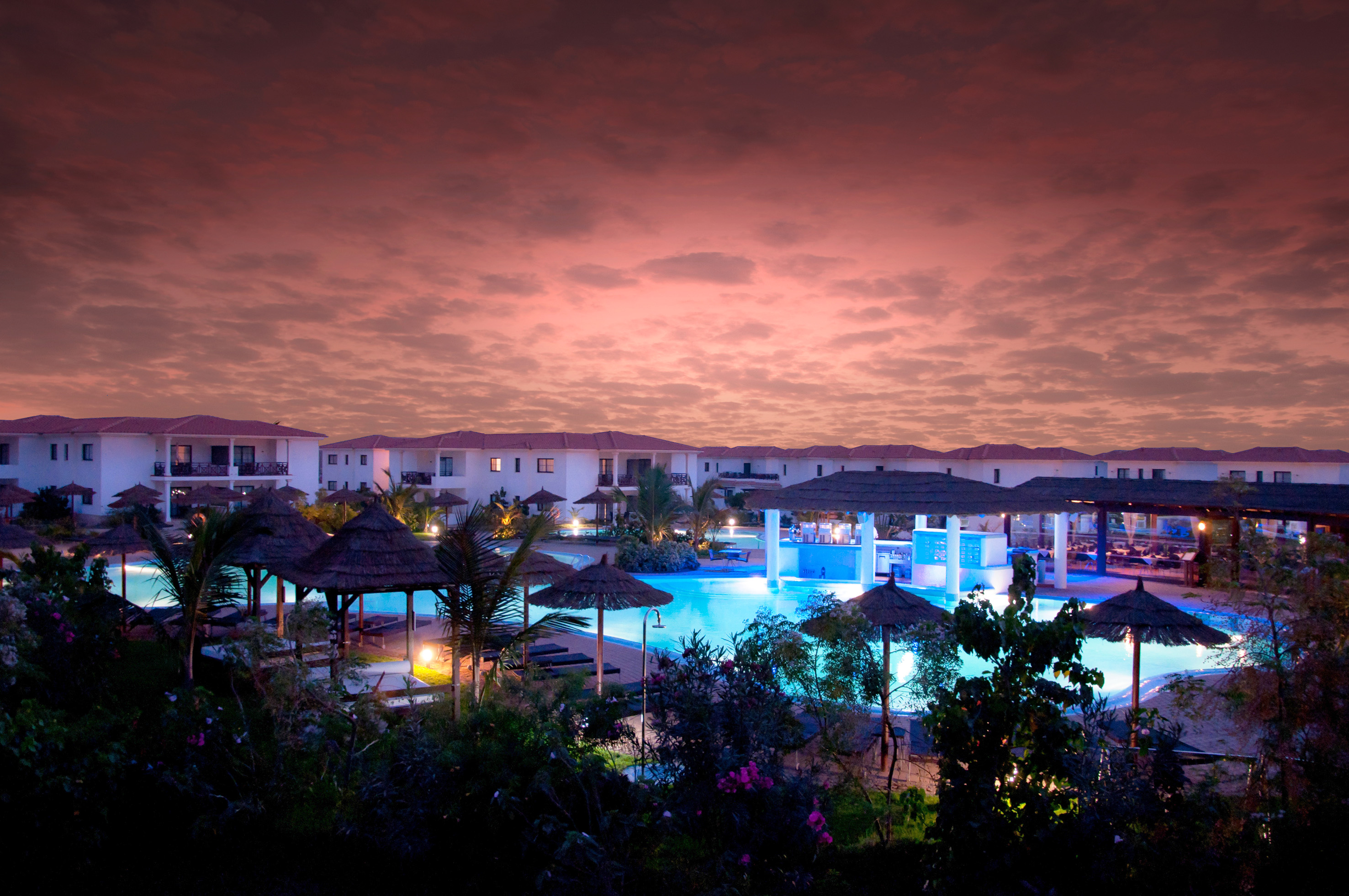 a pool with umbrellas and buildings in the background
