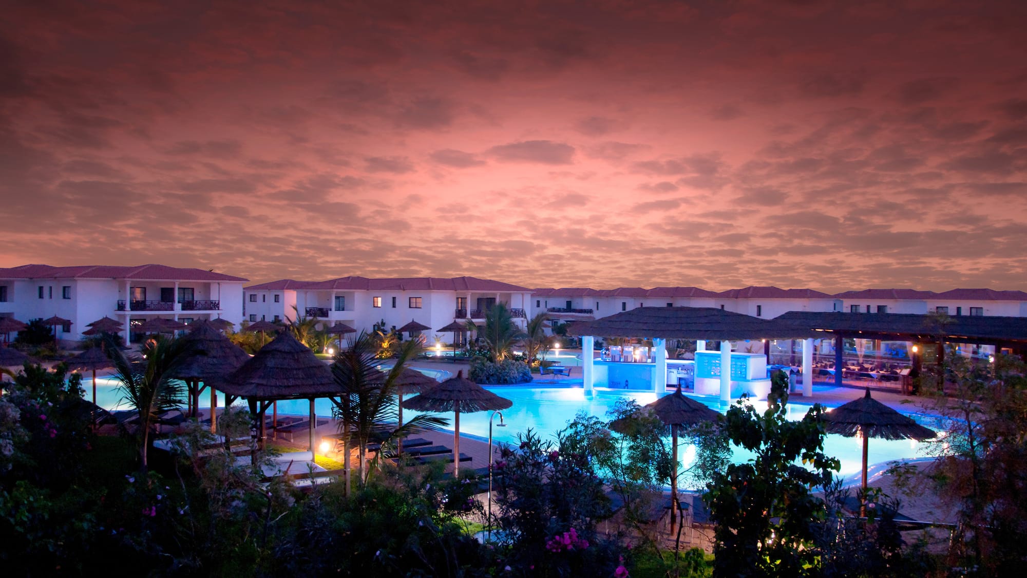 a pool with umbrellas and buildings in the background