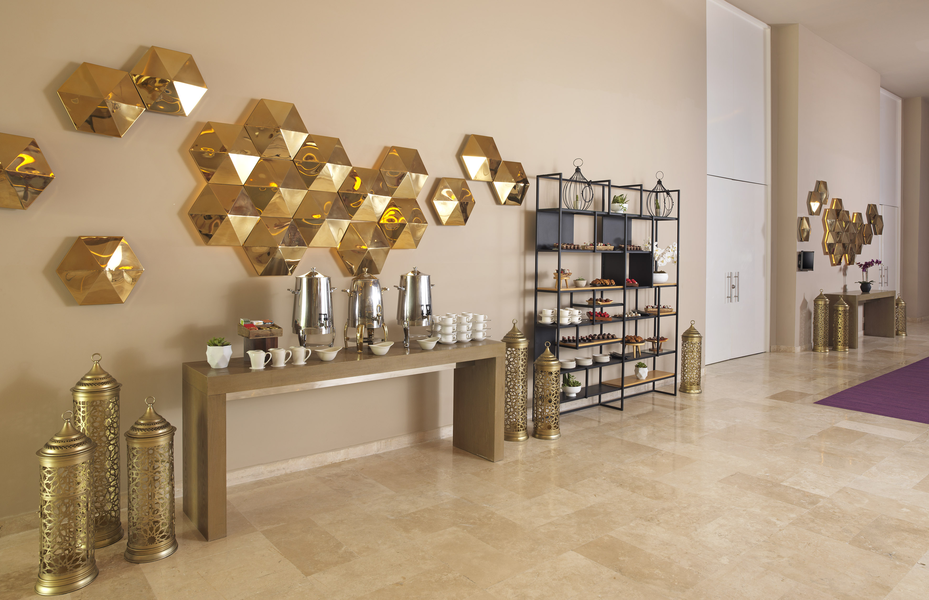 Modern catering display in a hotel lobby with golden hexagonal decor.
