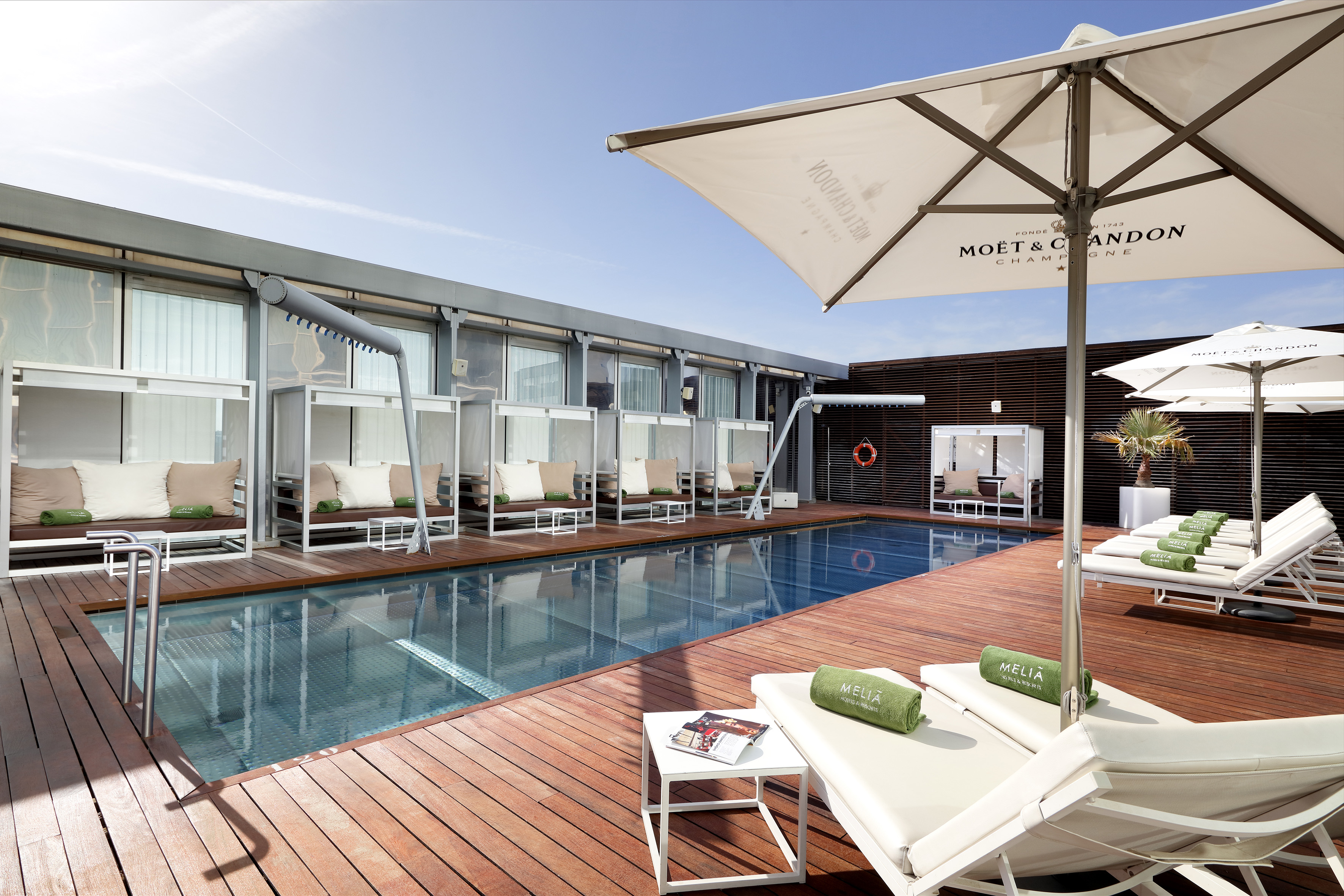 Meliá hotel rooftop pool deck with lounge chairs, cabanas, Moët umbrella.