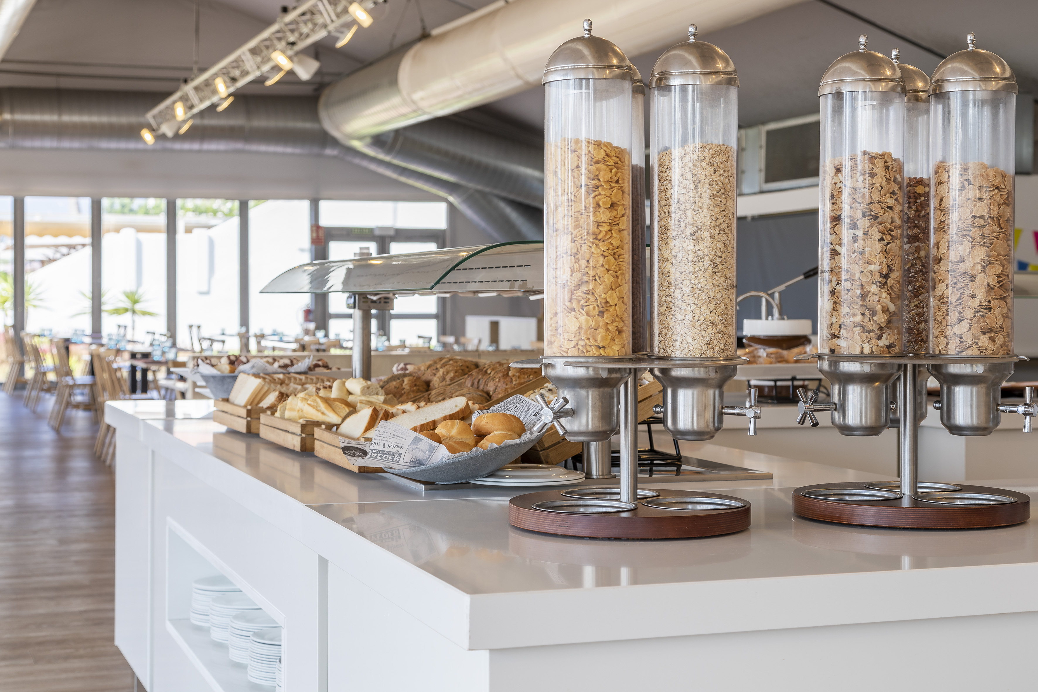 Breakfast buffet with cereal dispensers, fresh bread, and bright restaurant.