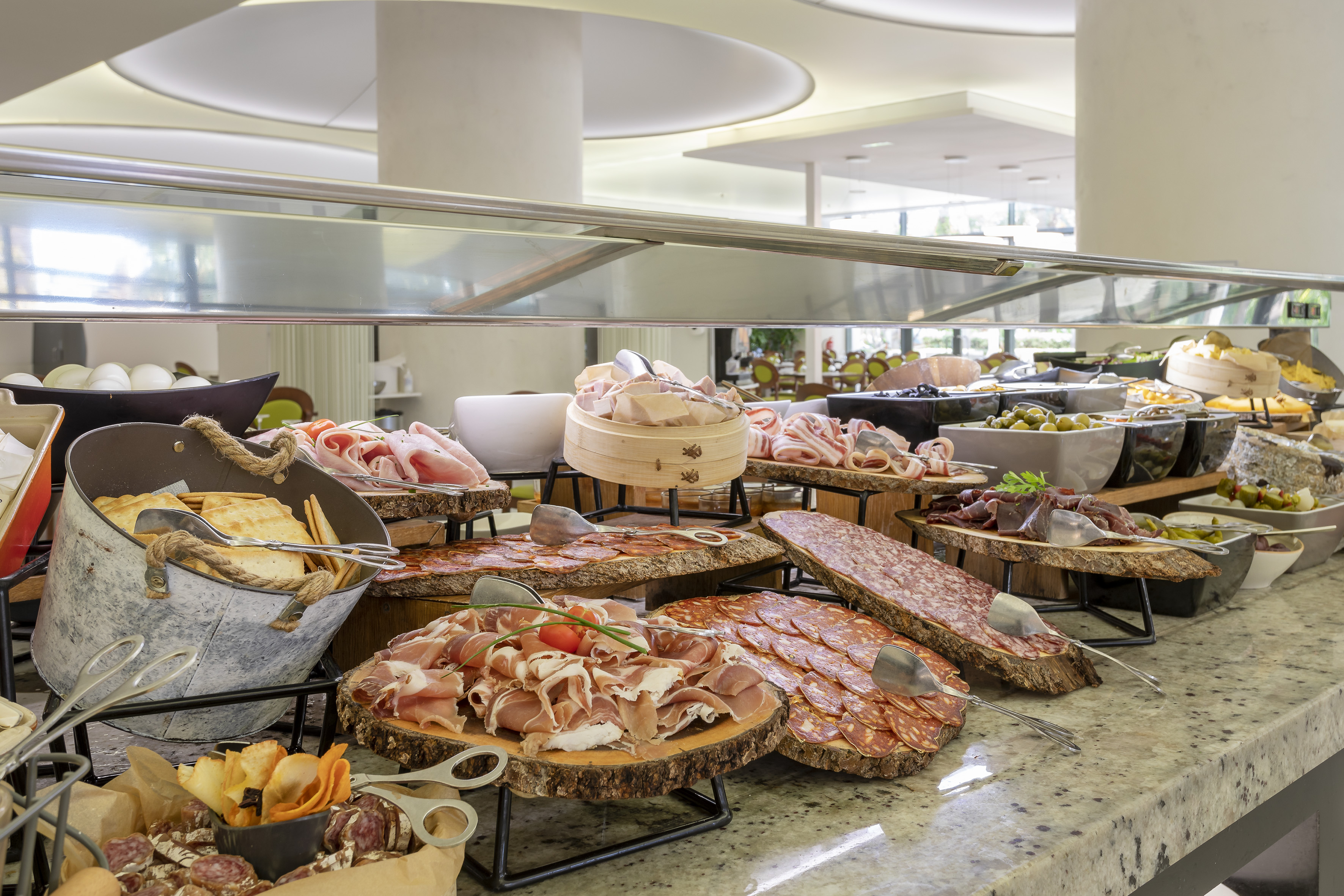 Hotel buffet displaying charcuterie, salami, prosciutto, cheeses, and olives.