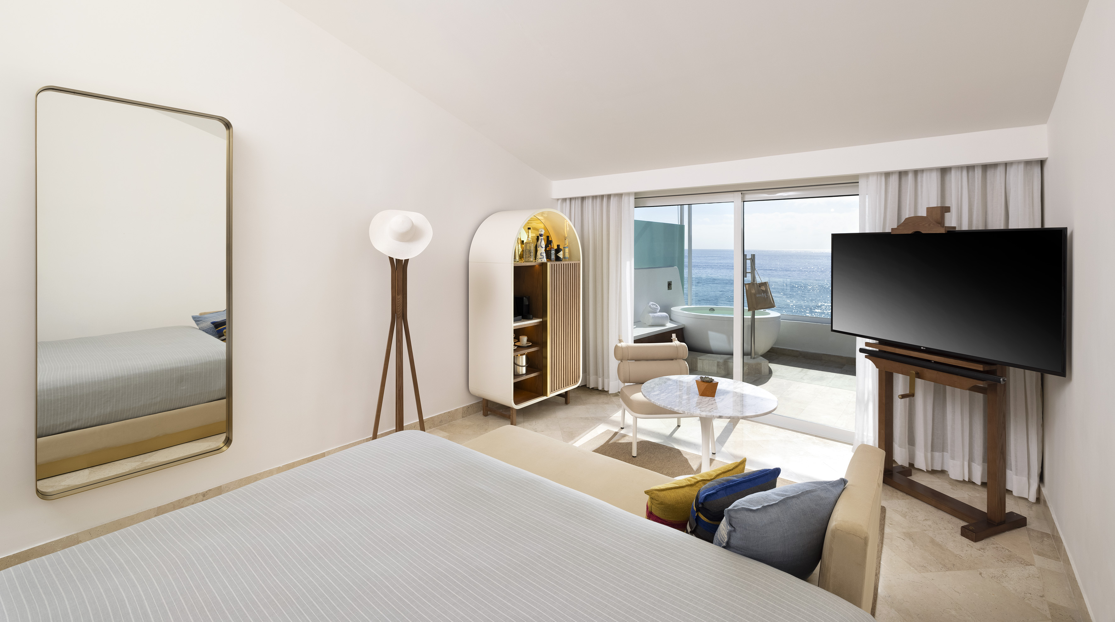 Luxury oceanfront hotel room, private balcony with outdoor tub, modern interior.