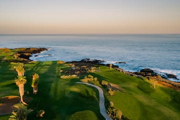 a golf course with a path and a body of water