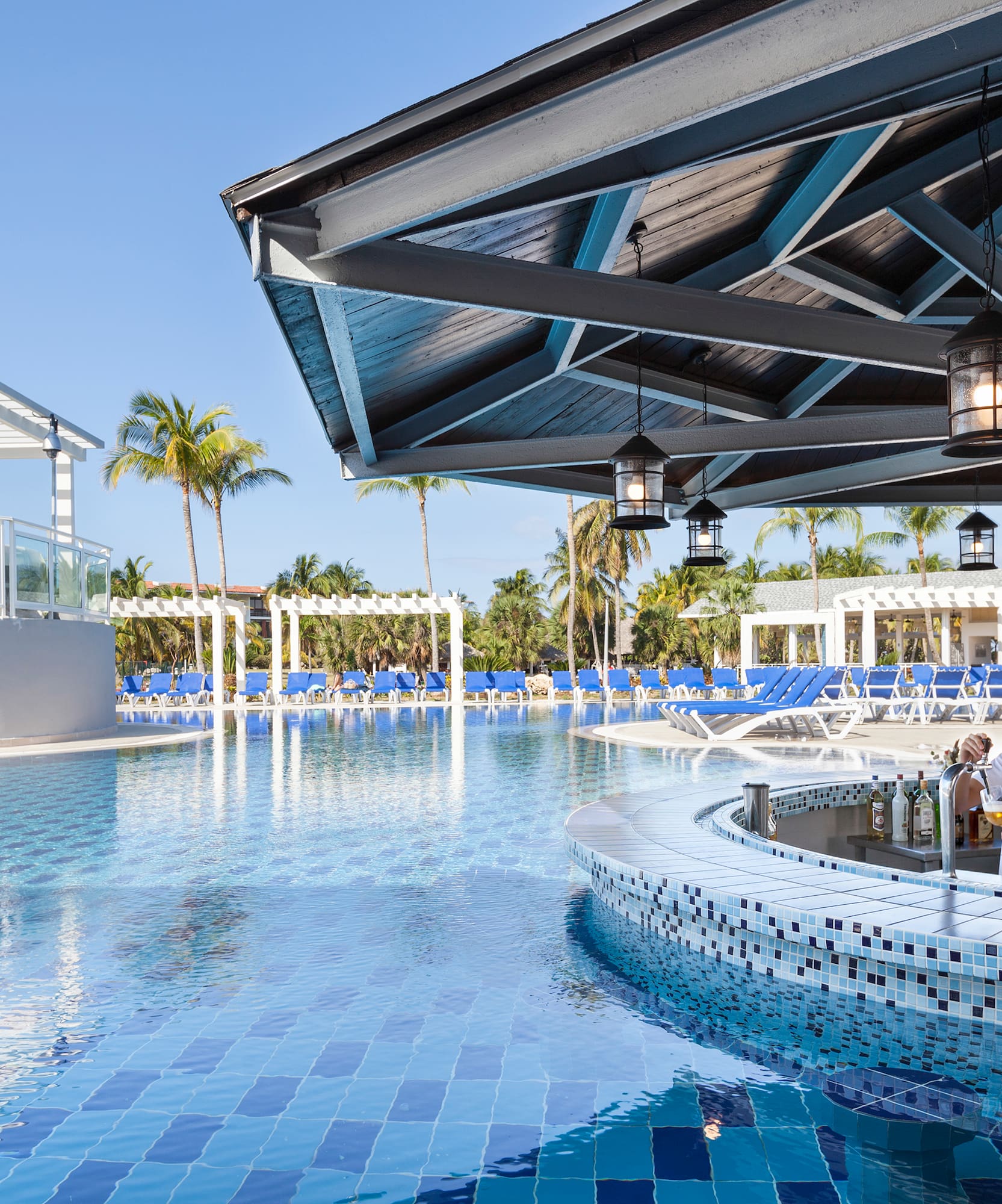 a man standing at a bar with a pool in the background