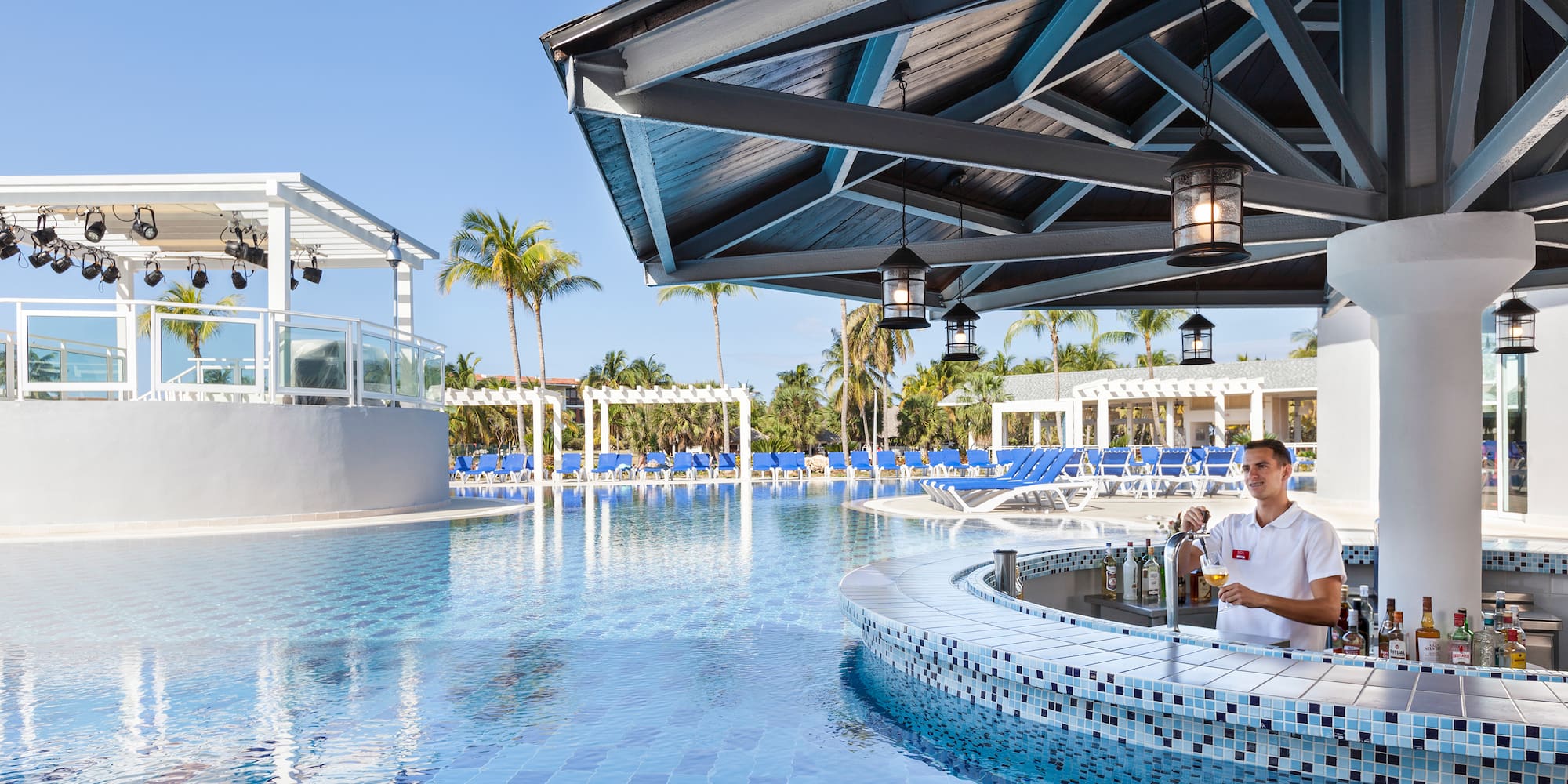a man standing at a bar with a pool in the background