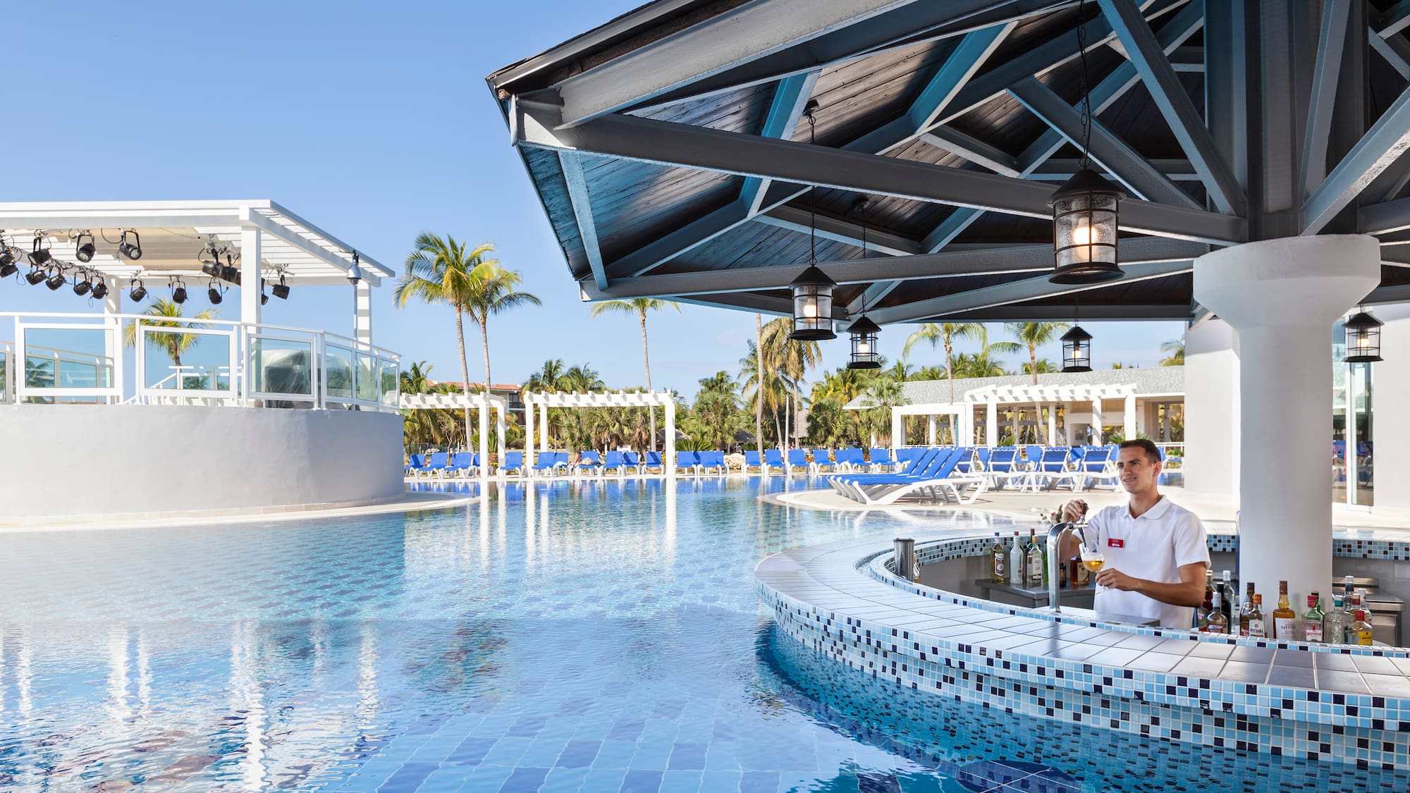 a man standing at a bar with a pool in the background