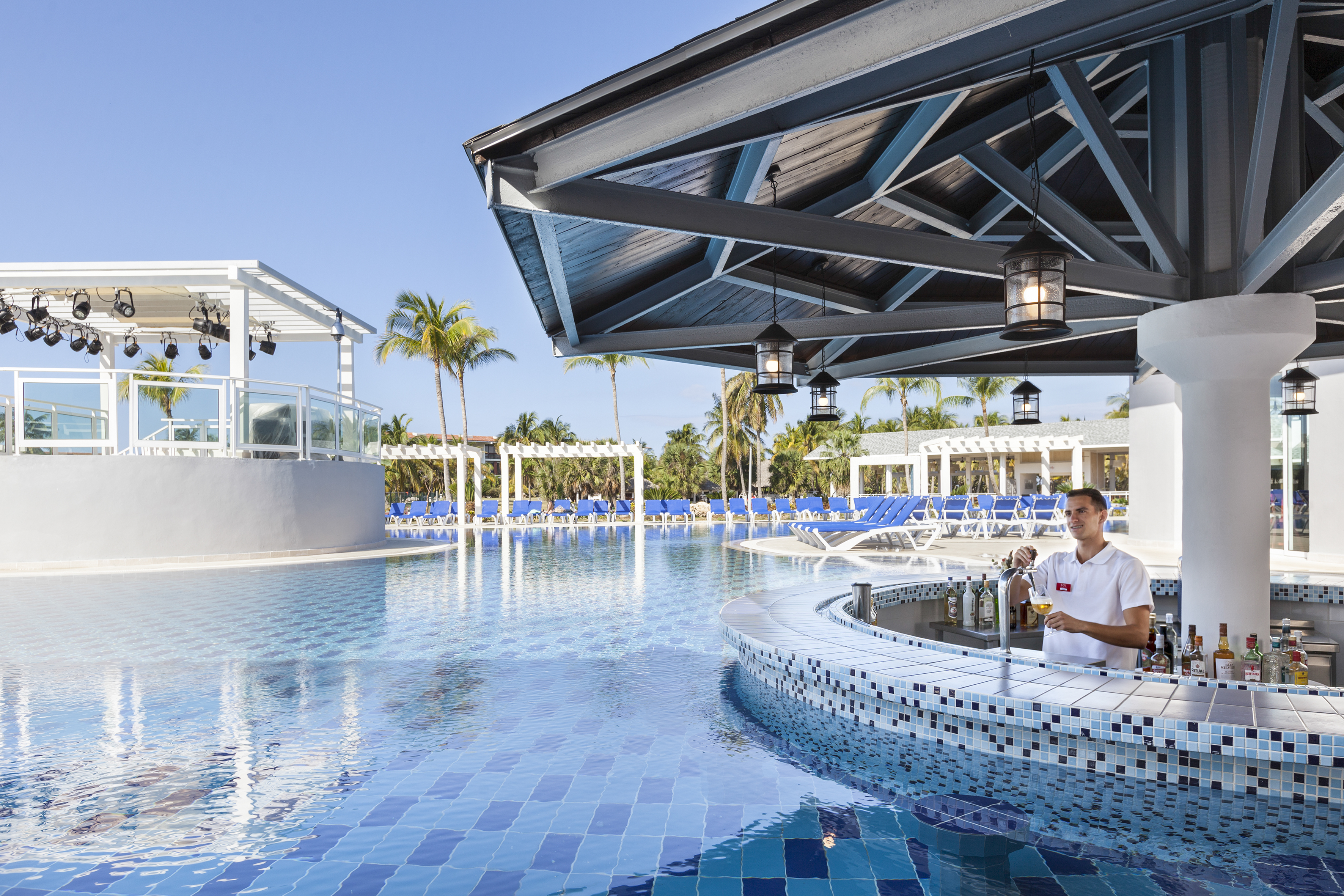 a man standing at a bar with a pool in the background