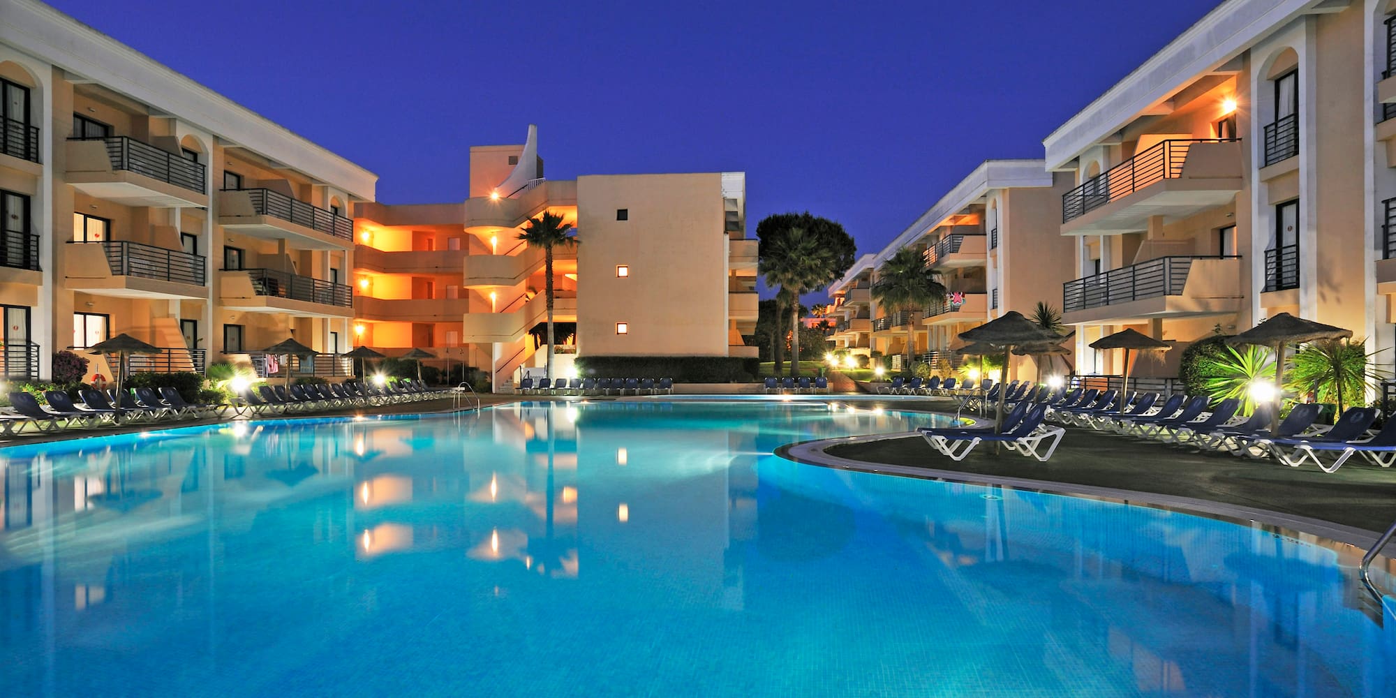a pool with chairs and a building in the background
