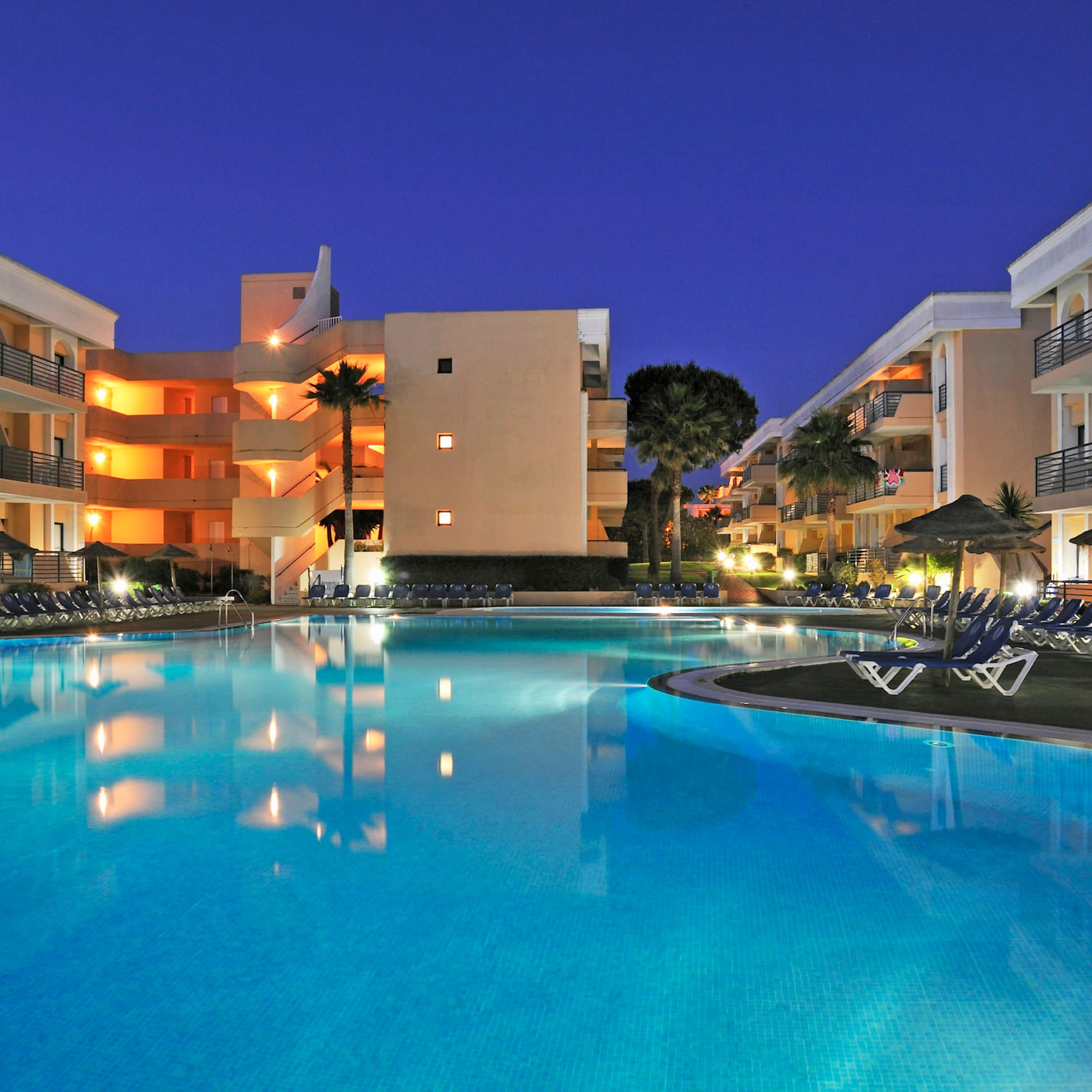 a pool with chairs and a building in the background