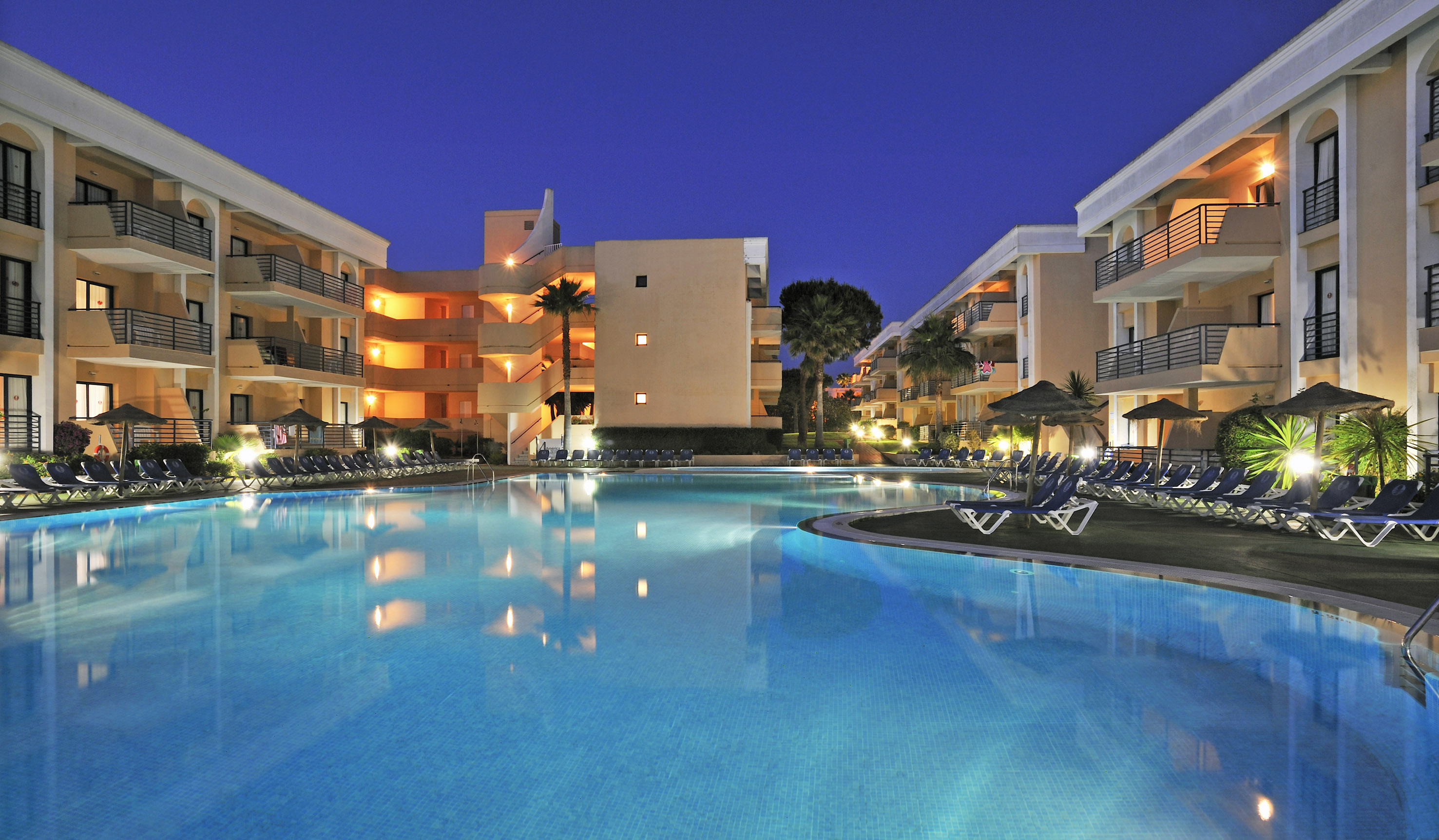 a pool with chairs and a building in the background