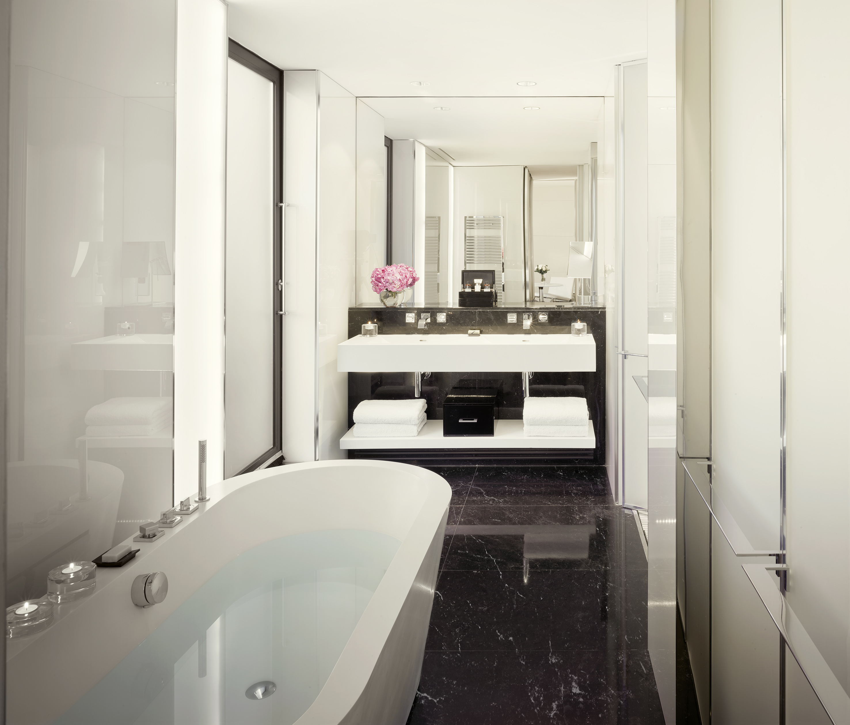 Luxury modern bathroom with white freestanding tub, black marble floor, double vanity.