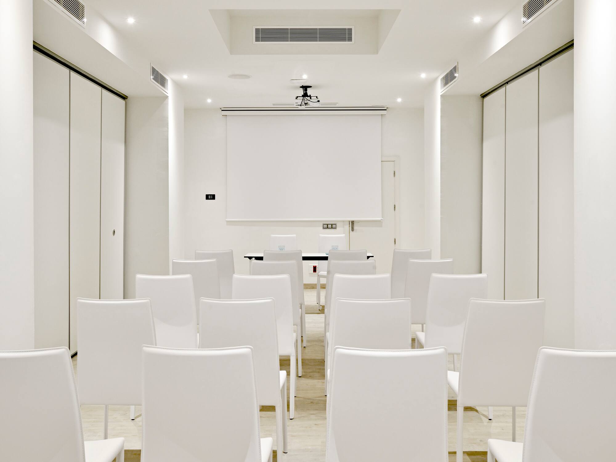 a room with white chairs and a projector screen