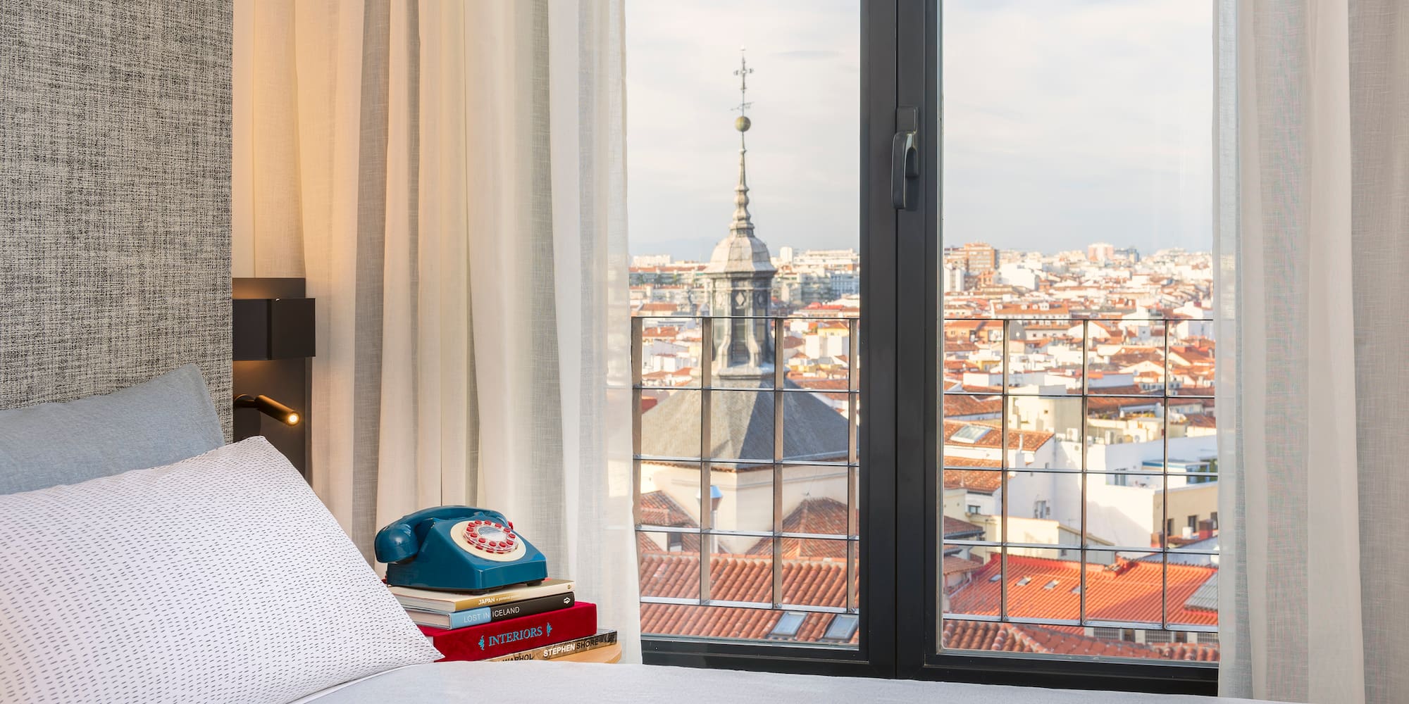 a bed with a phone and a view of a city