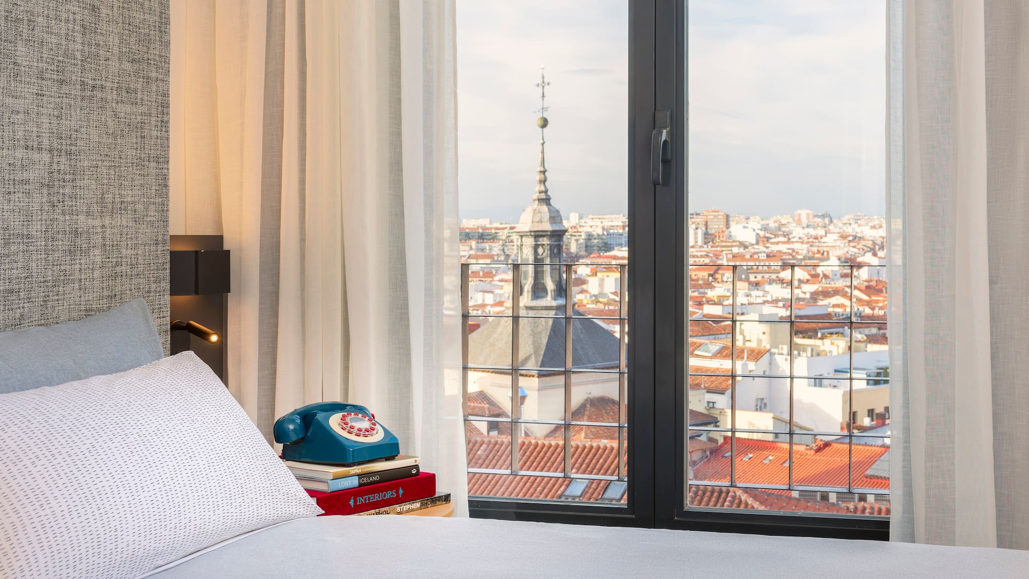 a bed with a phone and a view of a city