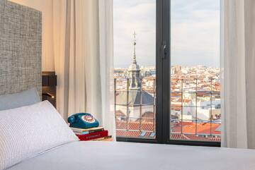 a bed, a phone, and a view of the city
