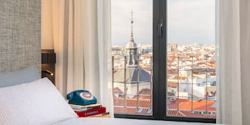 a bed with a phone and a view of a city