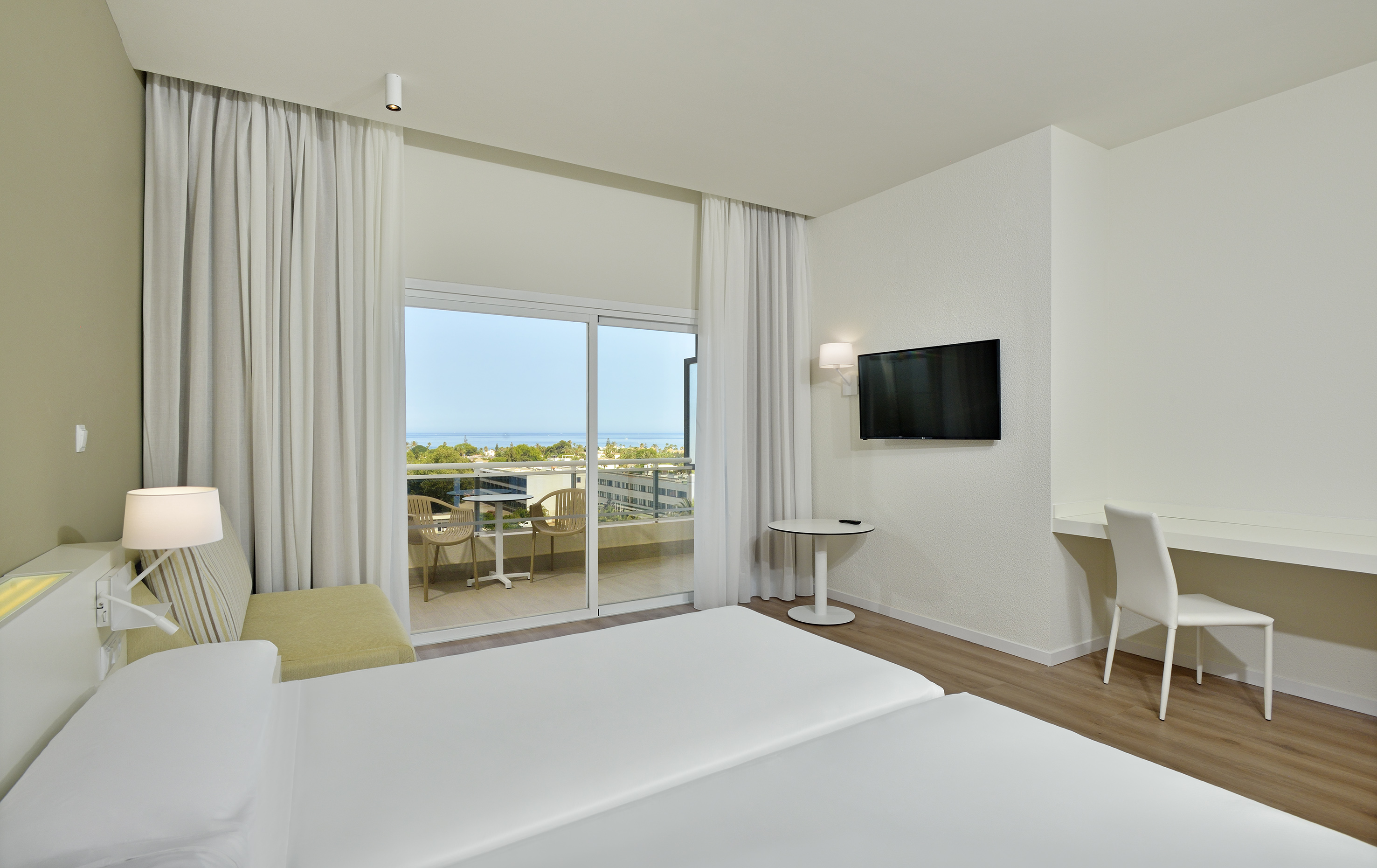 Hotel room with twin beds, private balcony, ocean view, and work desk.