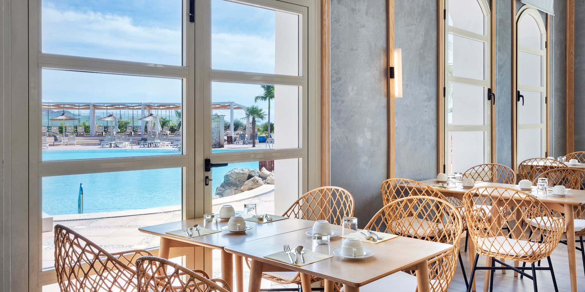 a table and chairs in a room with a view of water and a beach