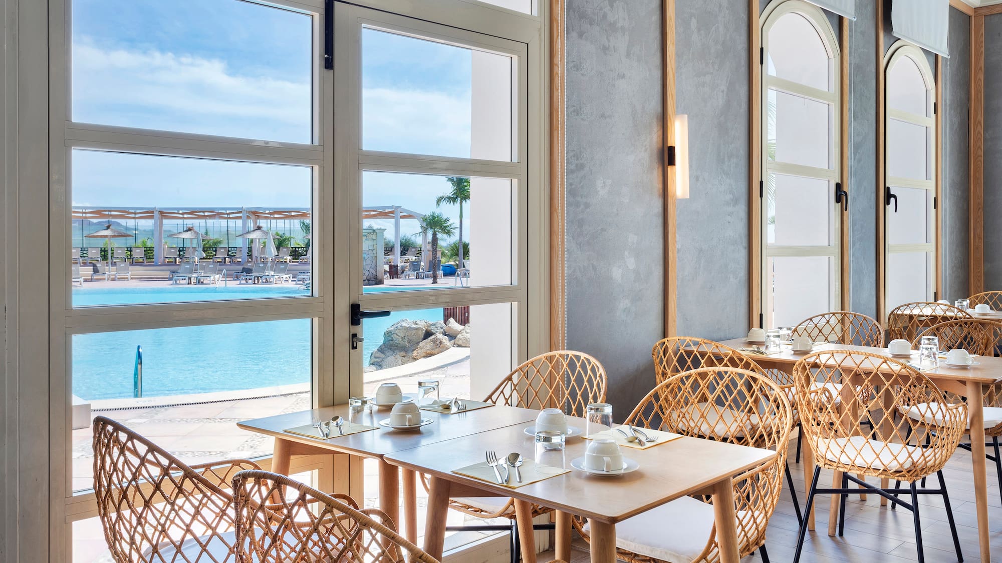 a table and chairs in a room with a view of water and a beach